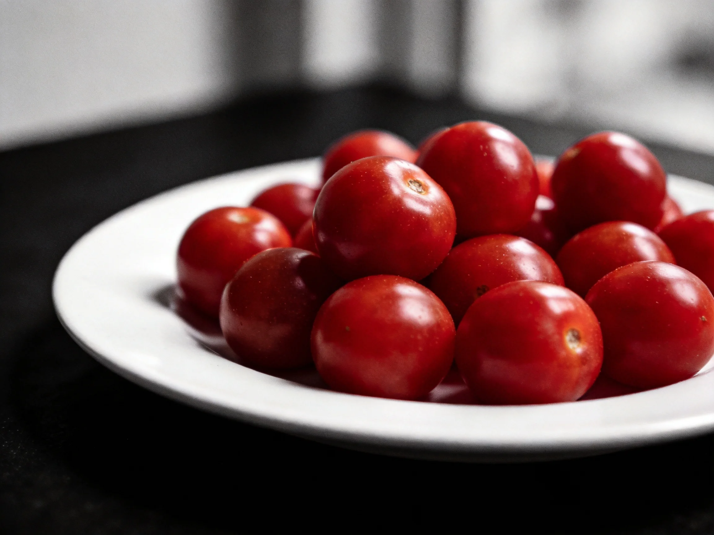 Vibrant red cherry tomatoes piled high on a white ceramic plate
