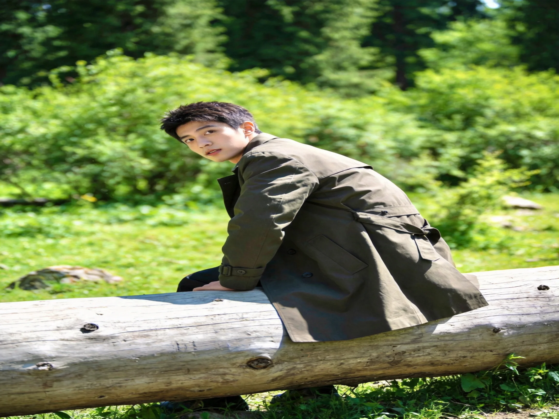 A man in an olive trench coat sits on a large wooden log amid lush green foliage