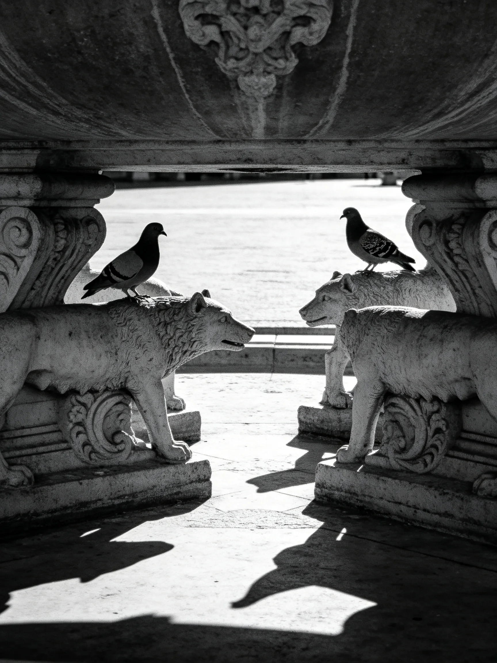 Stone wolf statues support an ornate structure with two pigeons perched