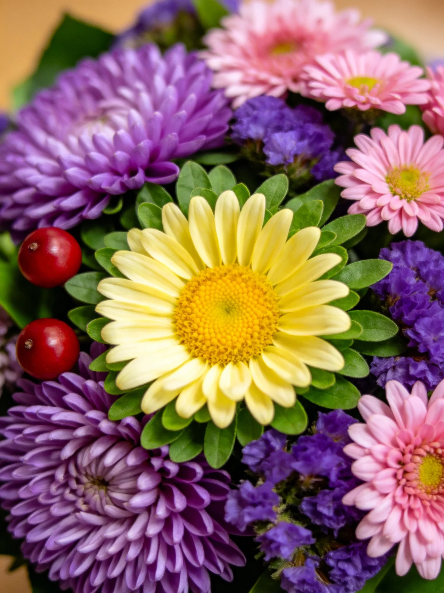 A vibrant bouquet with purple, pink, yellow flowers and red berries