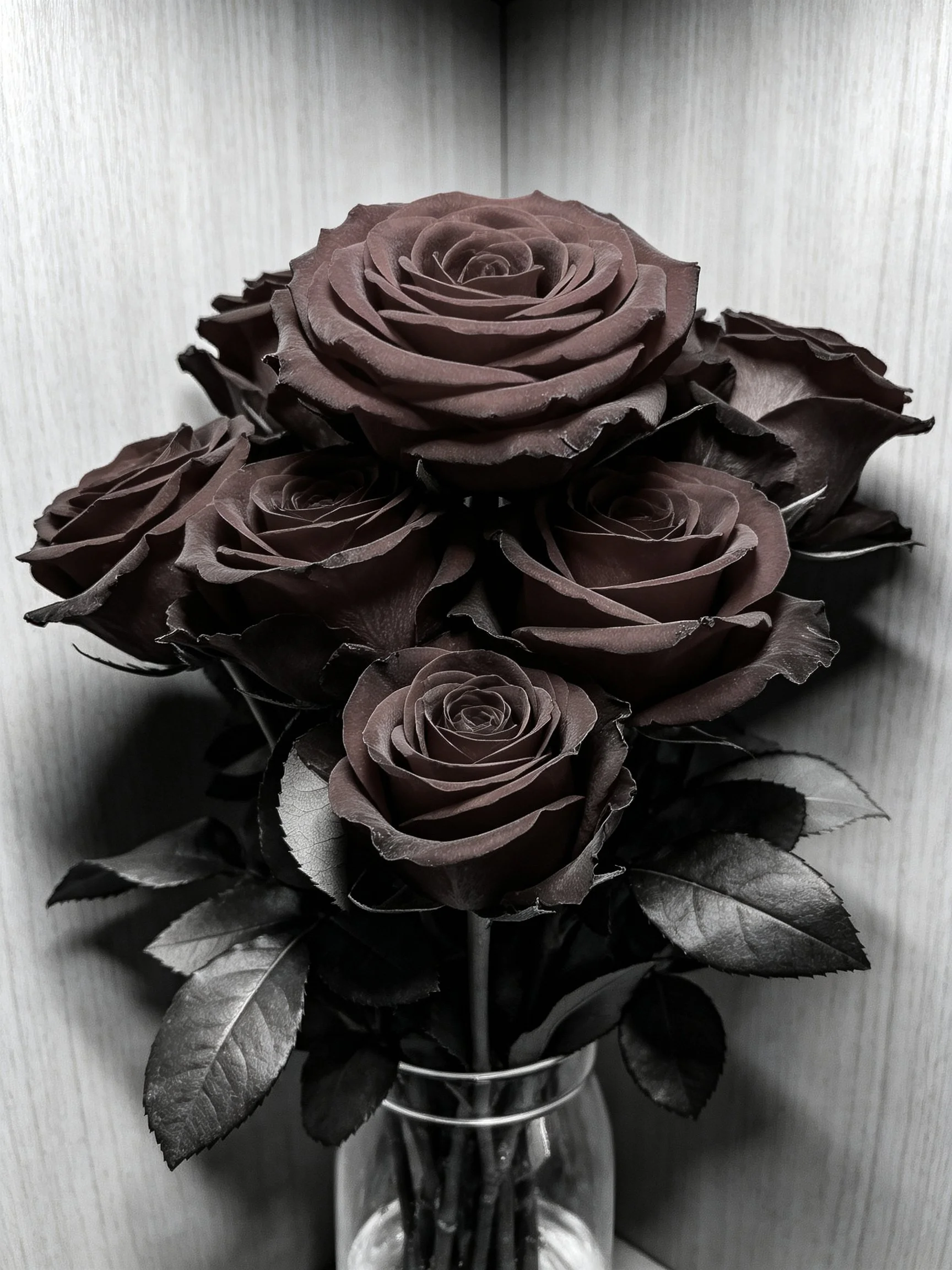 Dark brown roses arranged in a glass vase