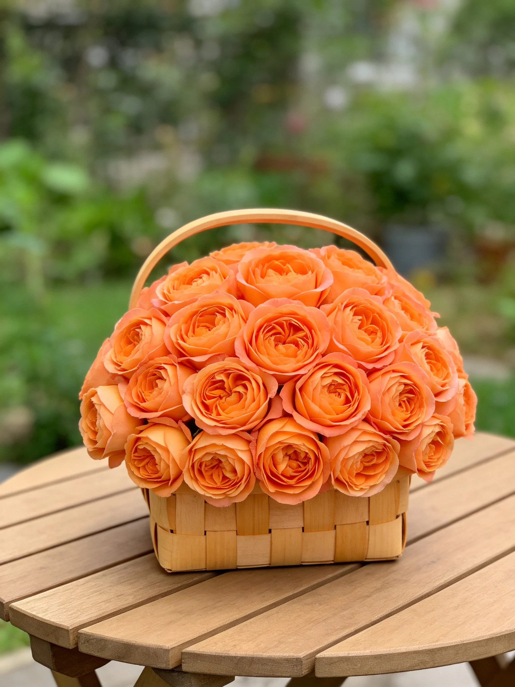 Vibrant orange roses arranged in a woven basket on a wooden table
