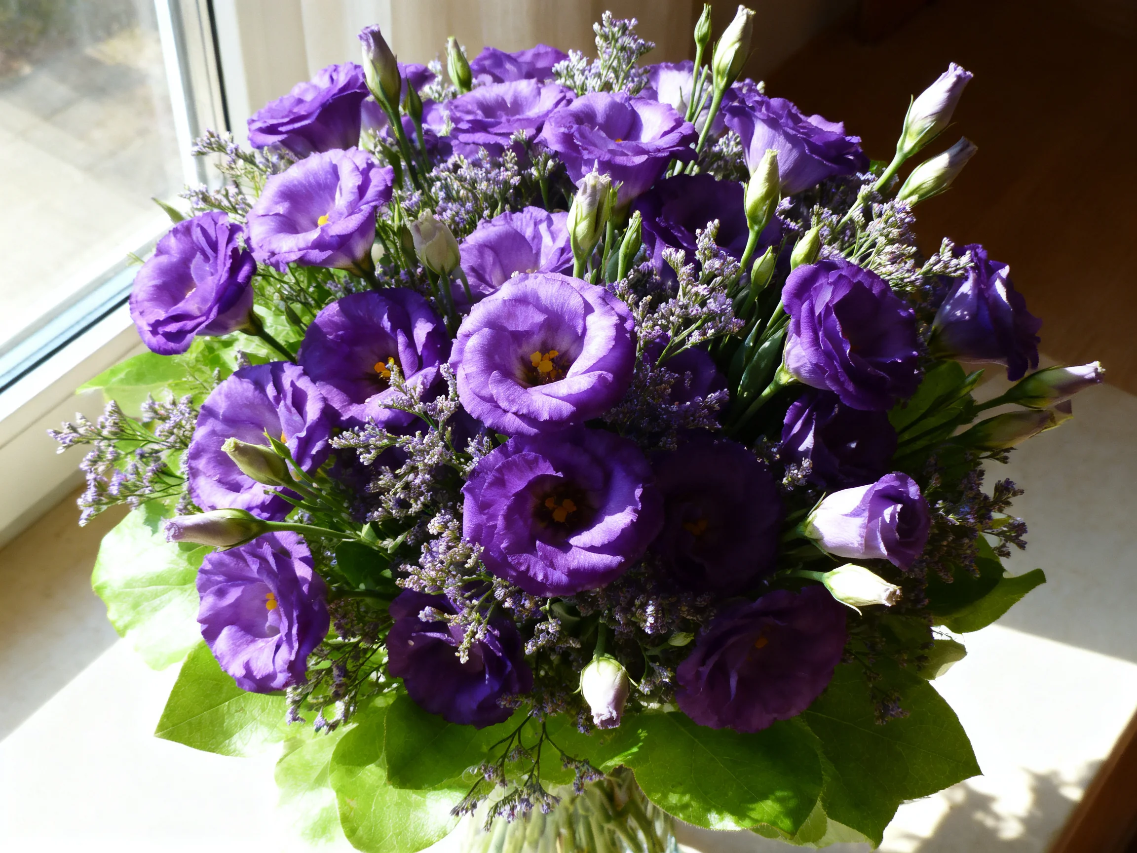 A lush bouquet of purple flowers beside a sunlit window