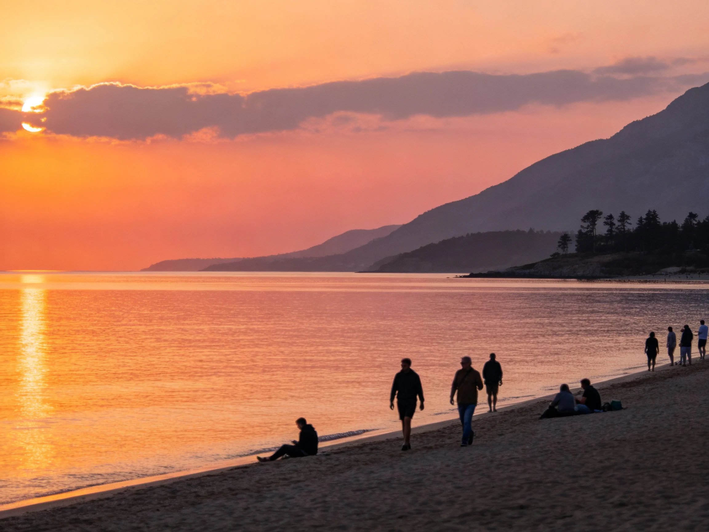 A Calming Beach Sunset with People and Mountains