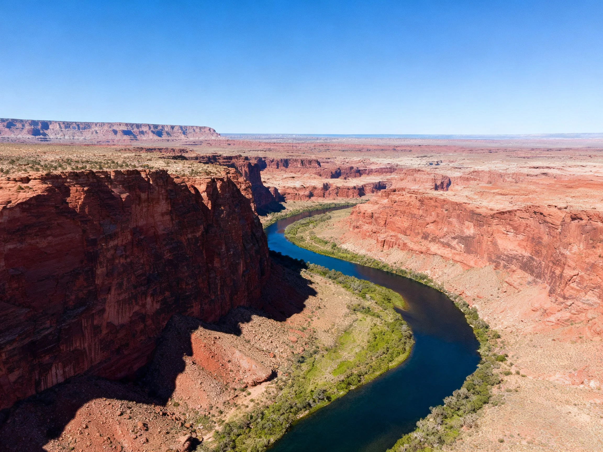 A Curved Blue River Flows Through Red Rock Canyons Under Clear Skies