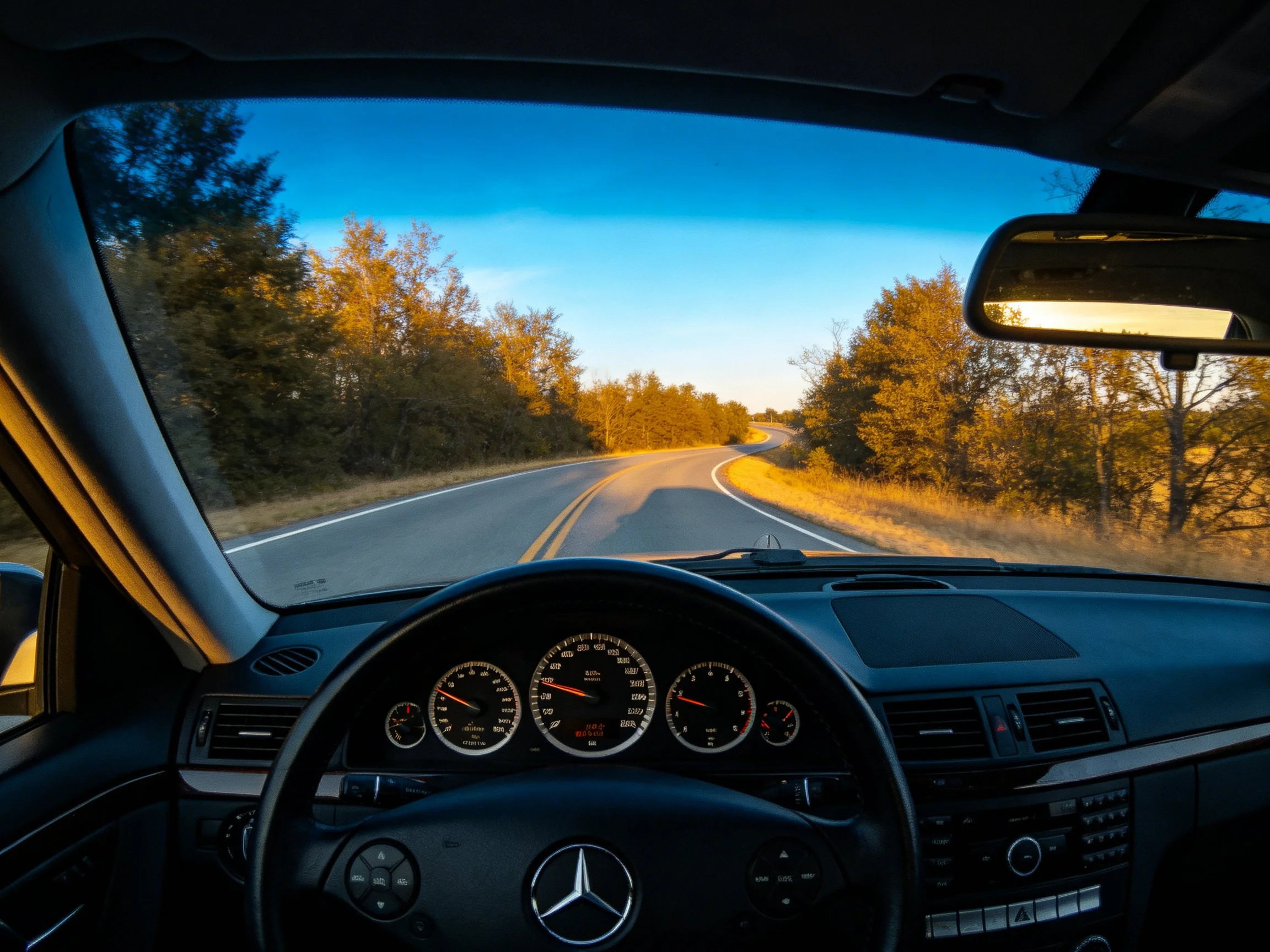 A Mercedes driving along a winding road during golden hour
