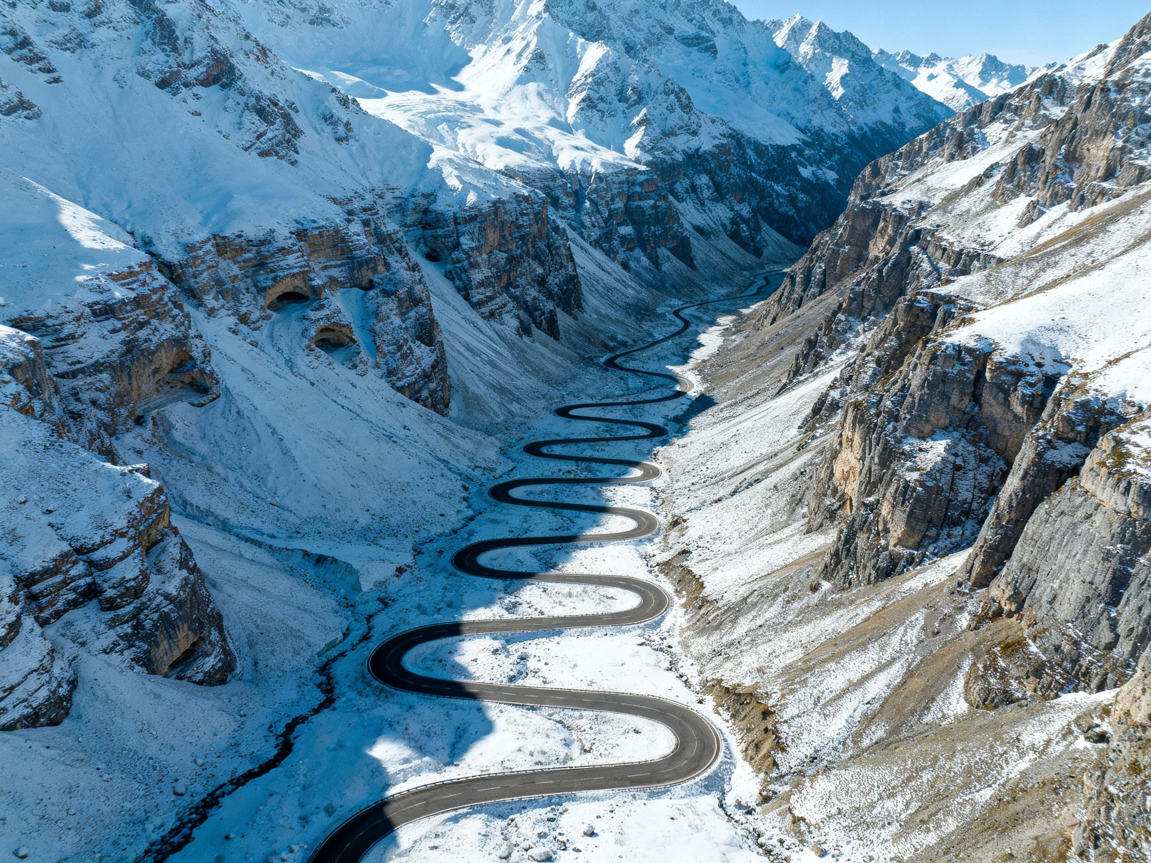 A Serpentine Road Winds Through Snow-Covered Mountain Valleys