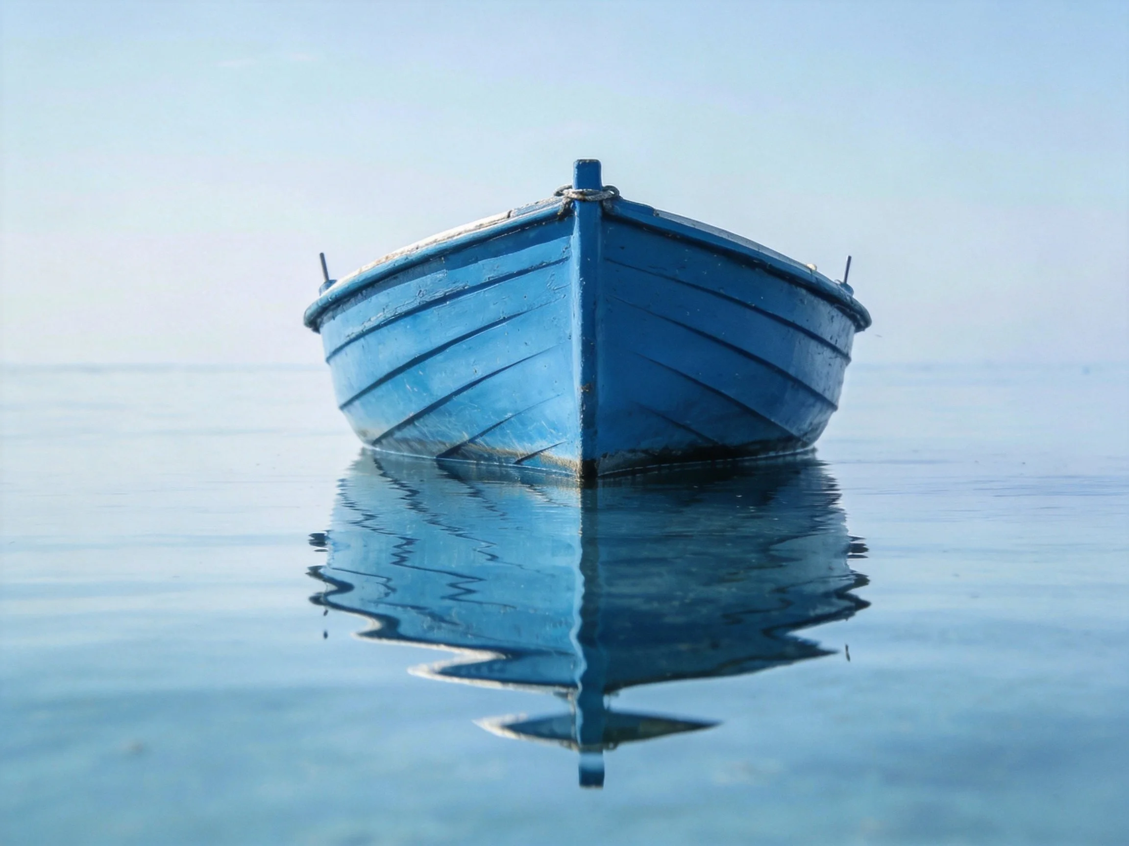 A blue wooden boat floats on calm, reflective water