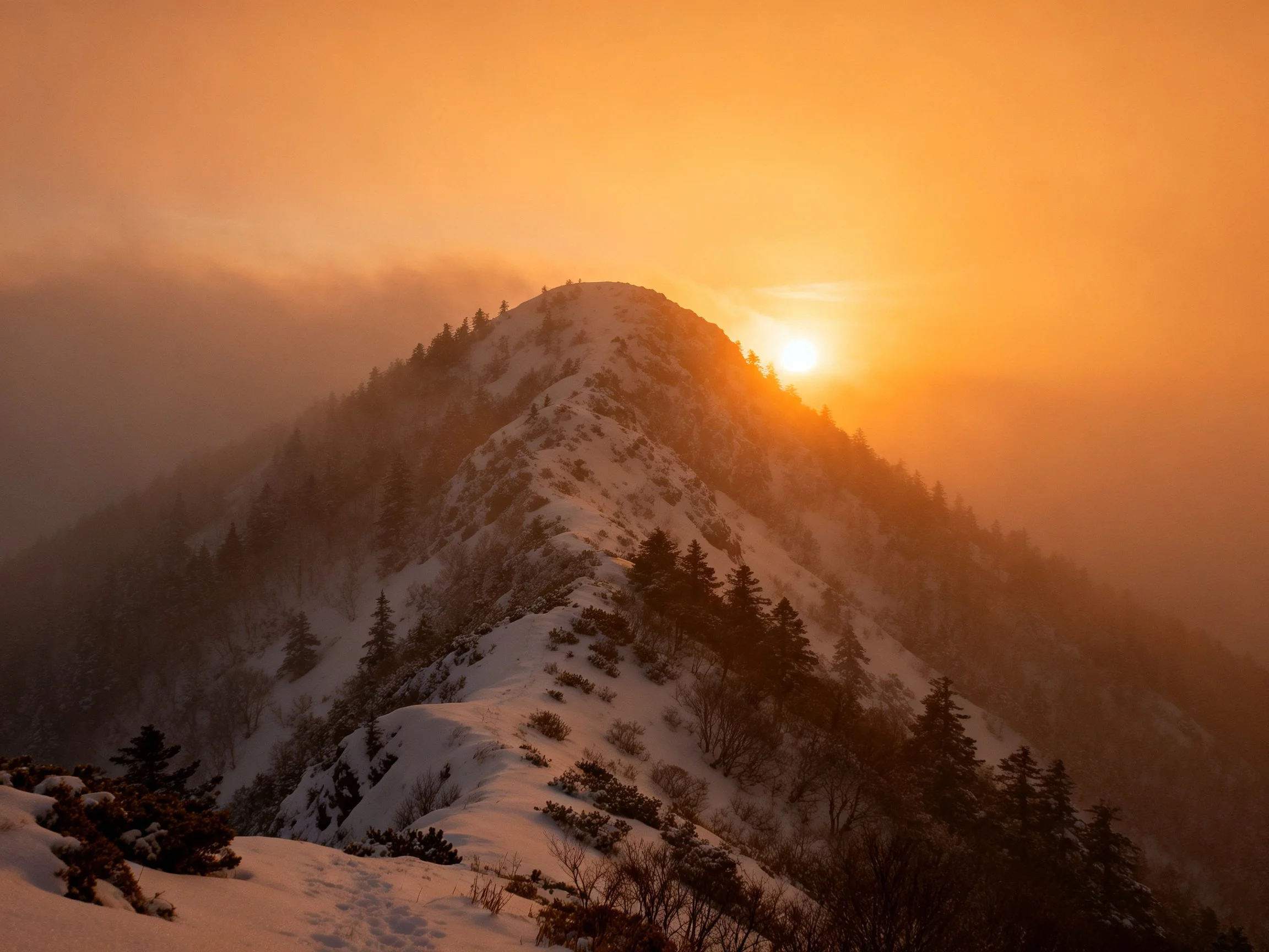 A golden sunrise illuminates a snow-capped mountain ridge