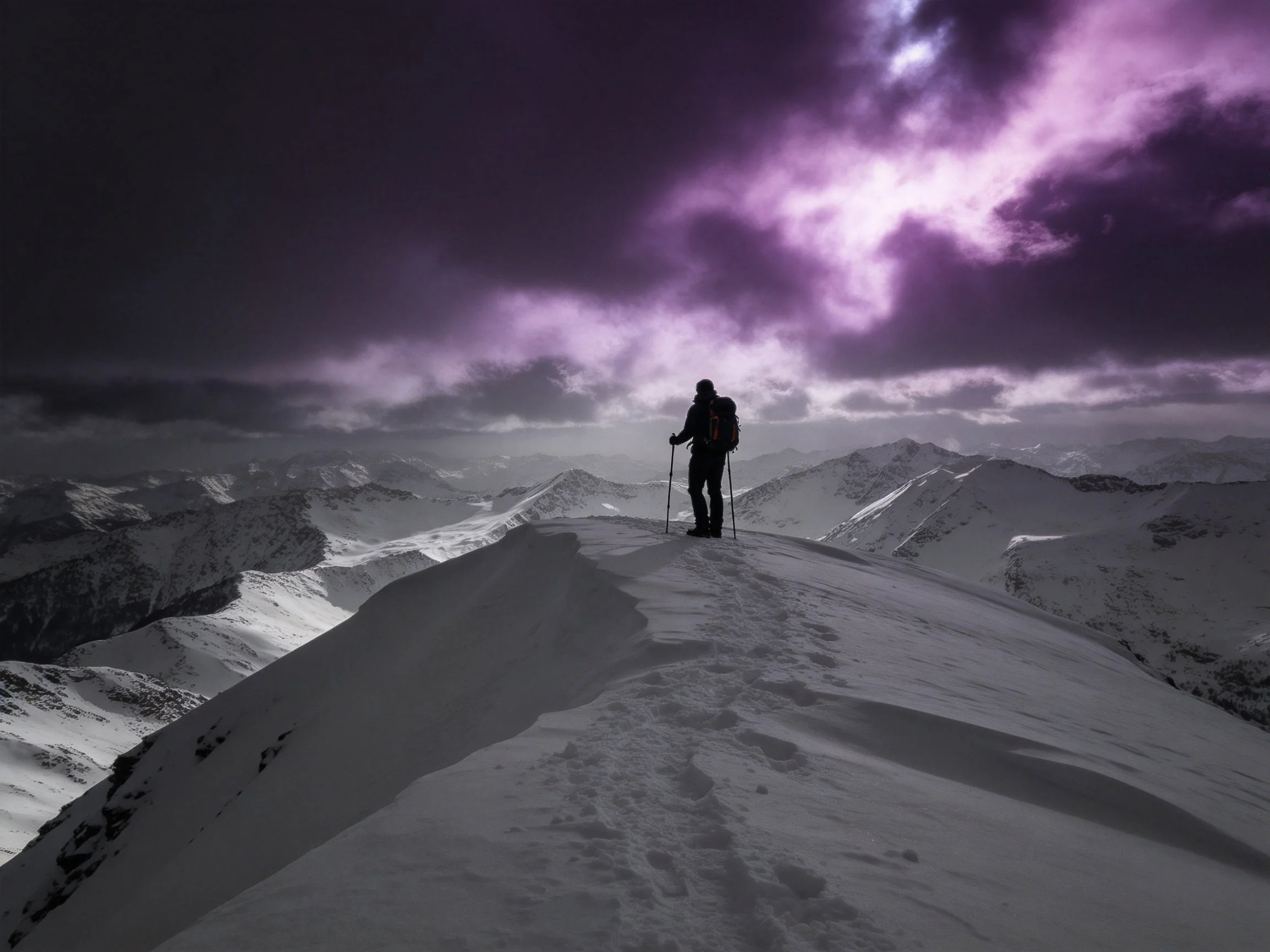 A hiker stands atop a snow-covered mountain ridge under a dramatic purple sky