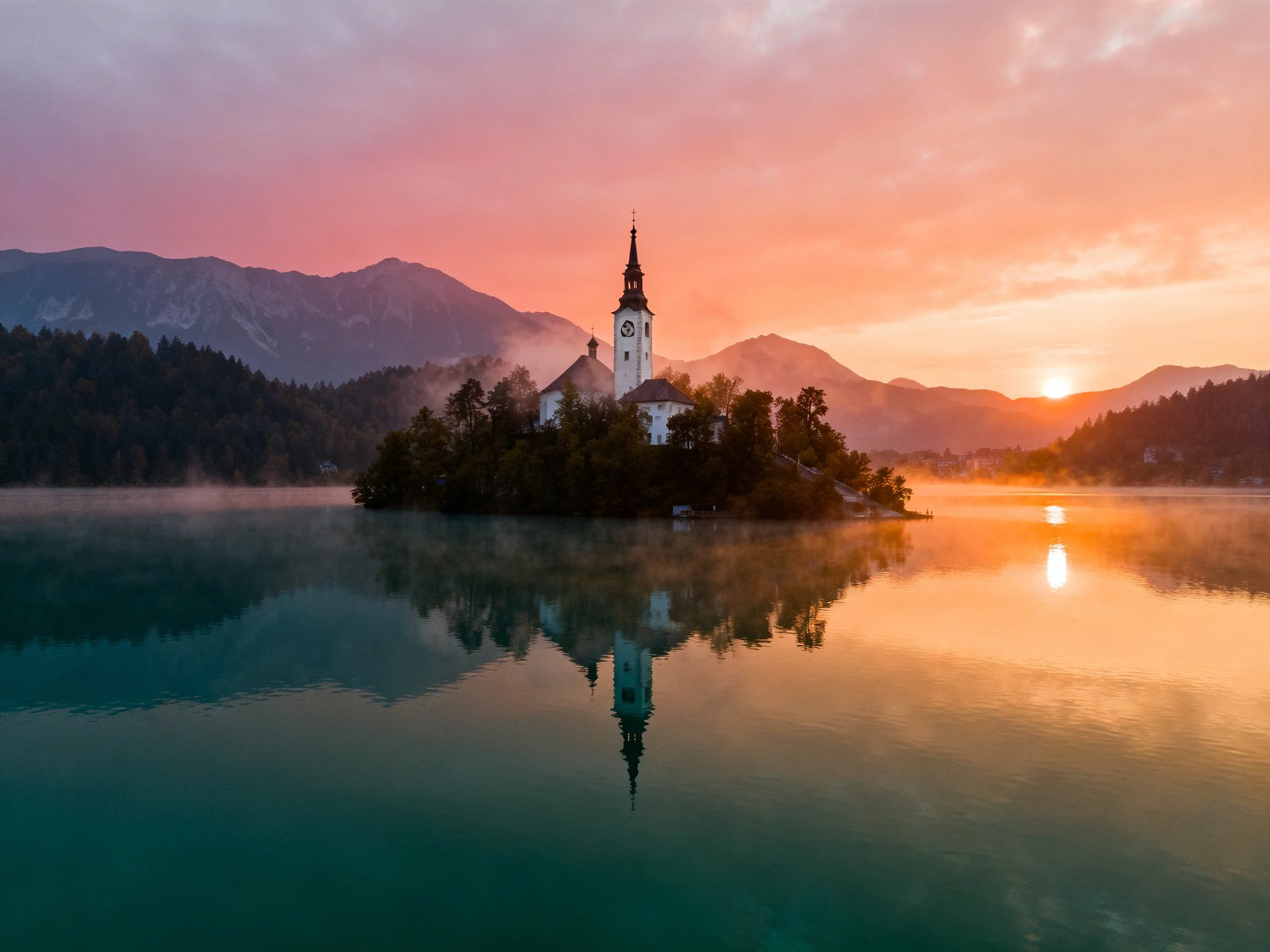 A historic church on a small island in a misty lake at dawn