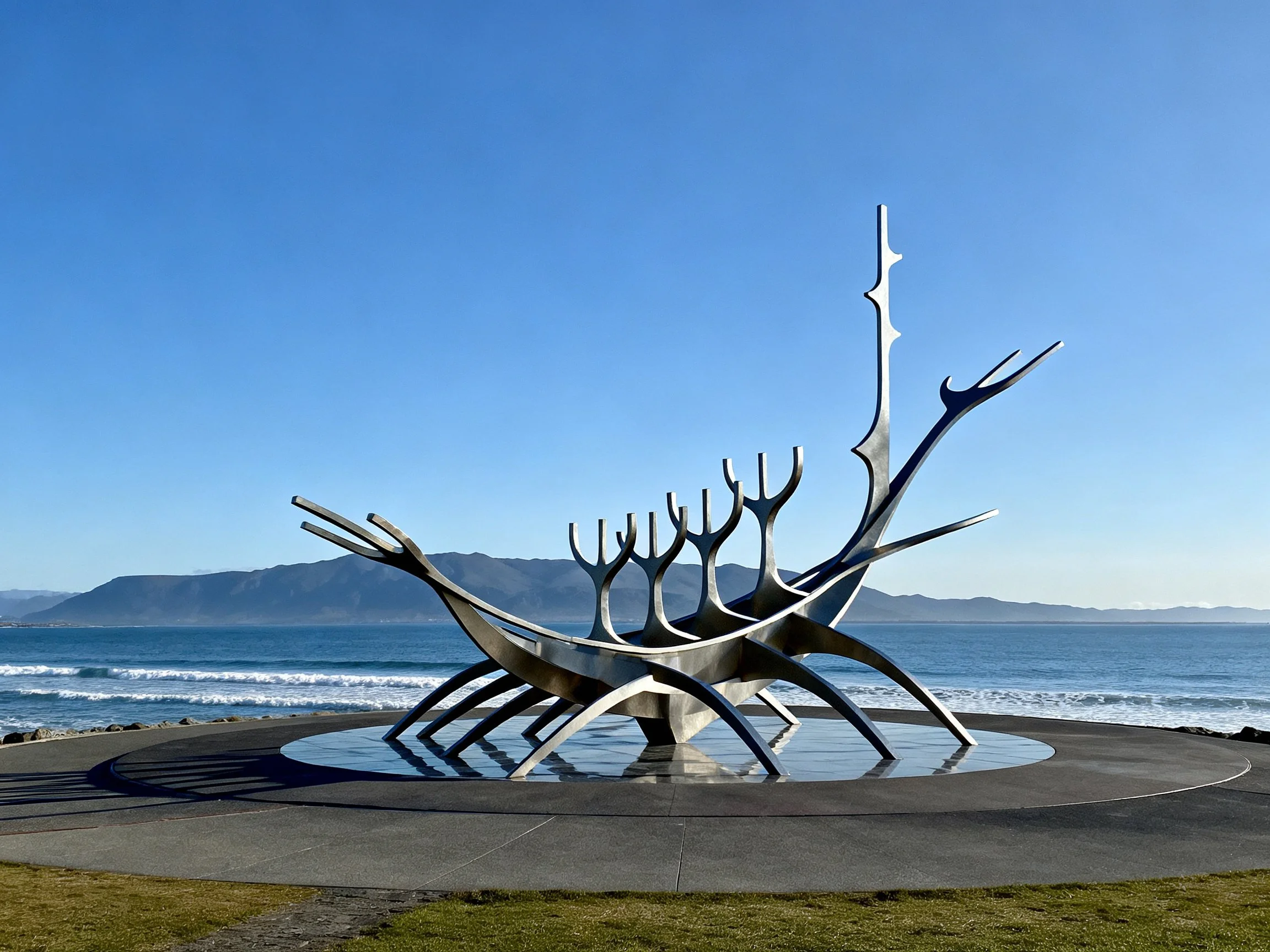 A large silver abstract sculpture by the coastal shore