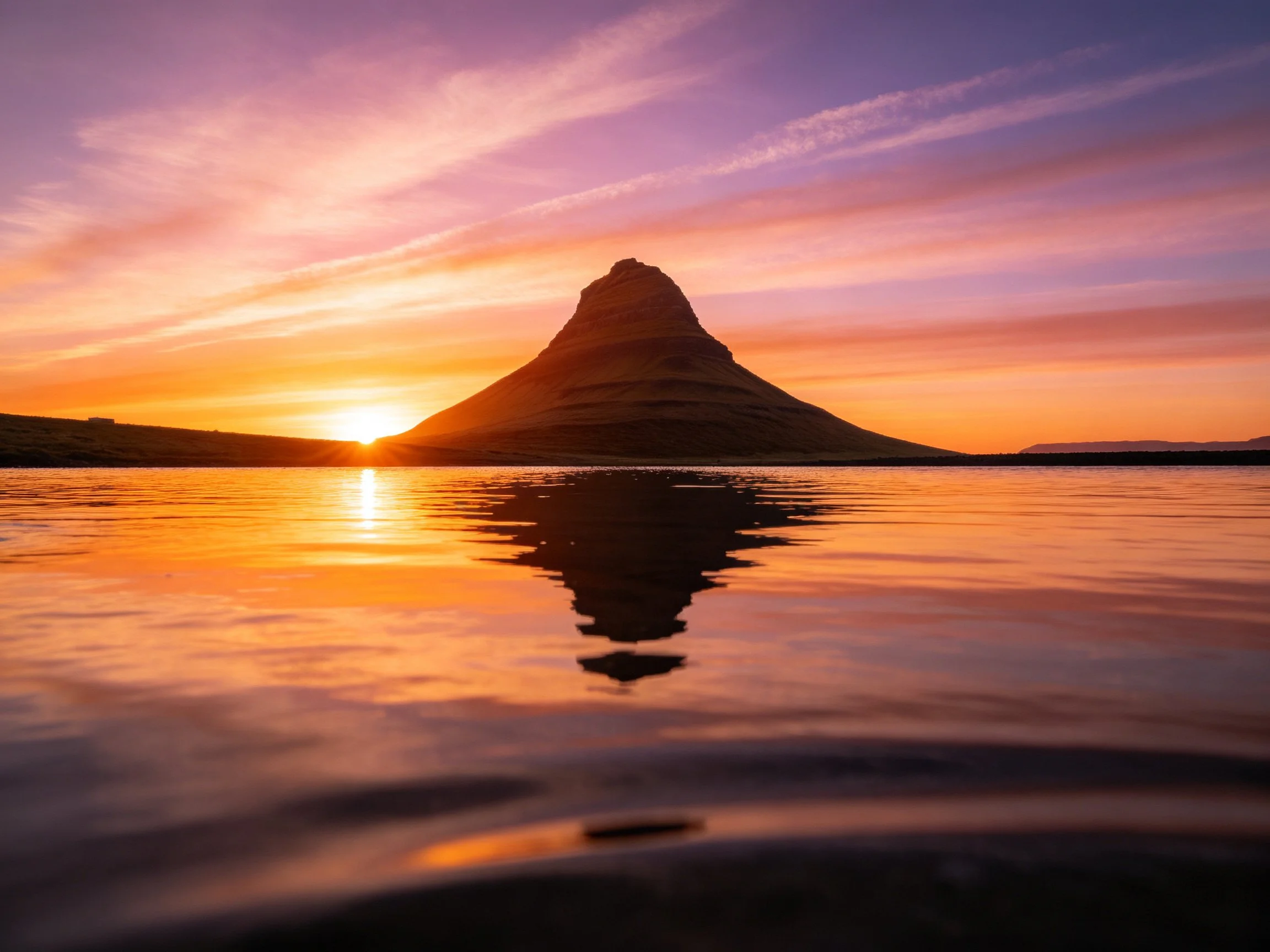 A majestic conical mountain reflected in calm waters at sunset