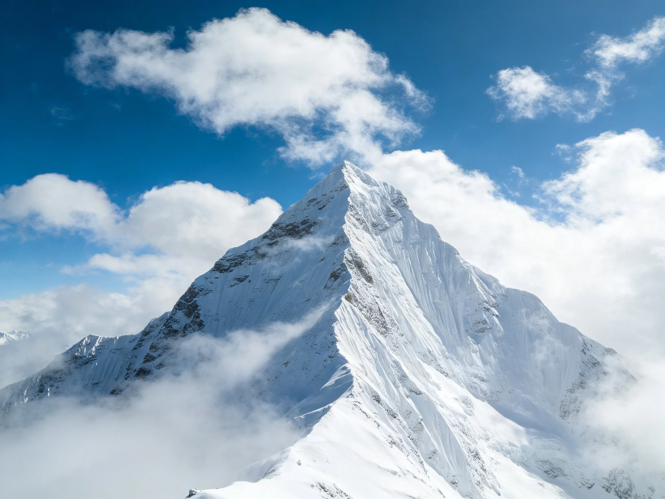 A majestic snow-capped peak rises beneath bright blue skies