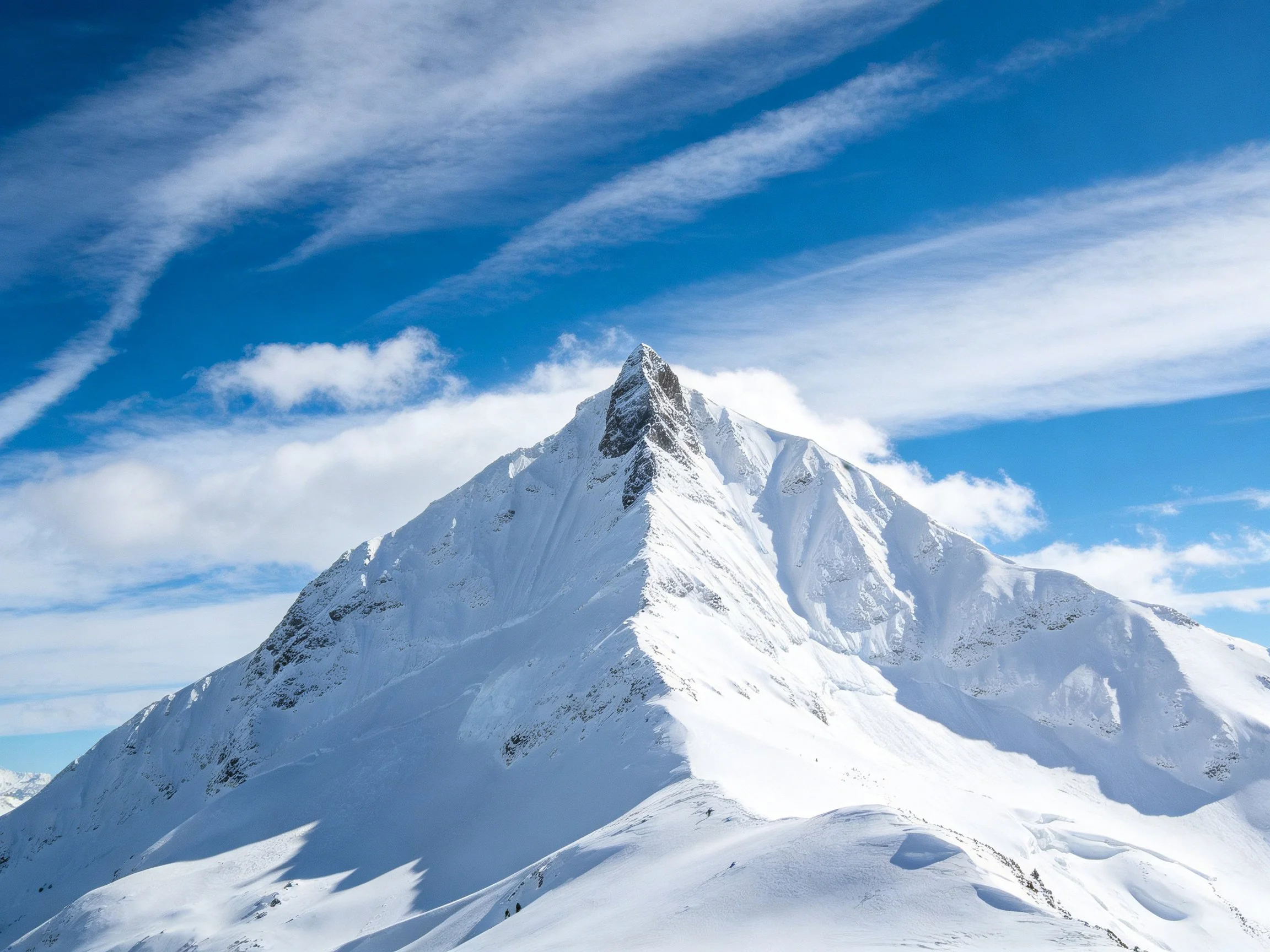 A majestic snow-covered mountain peak against a bright blue sky