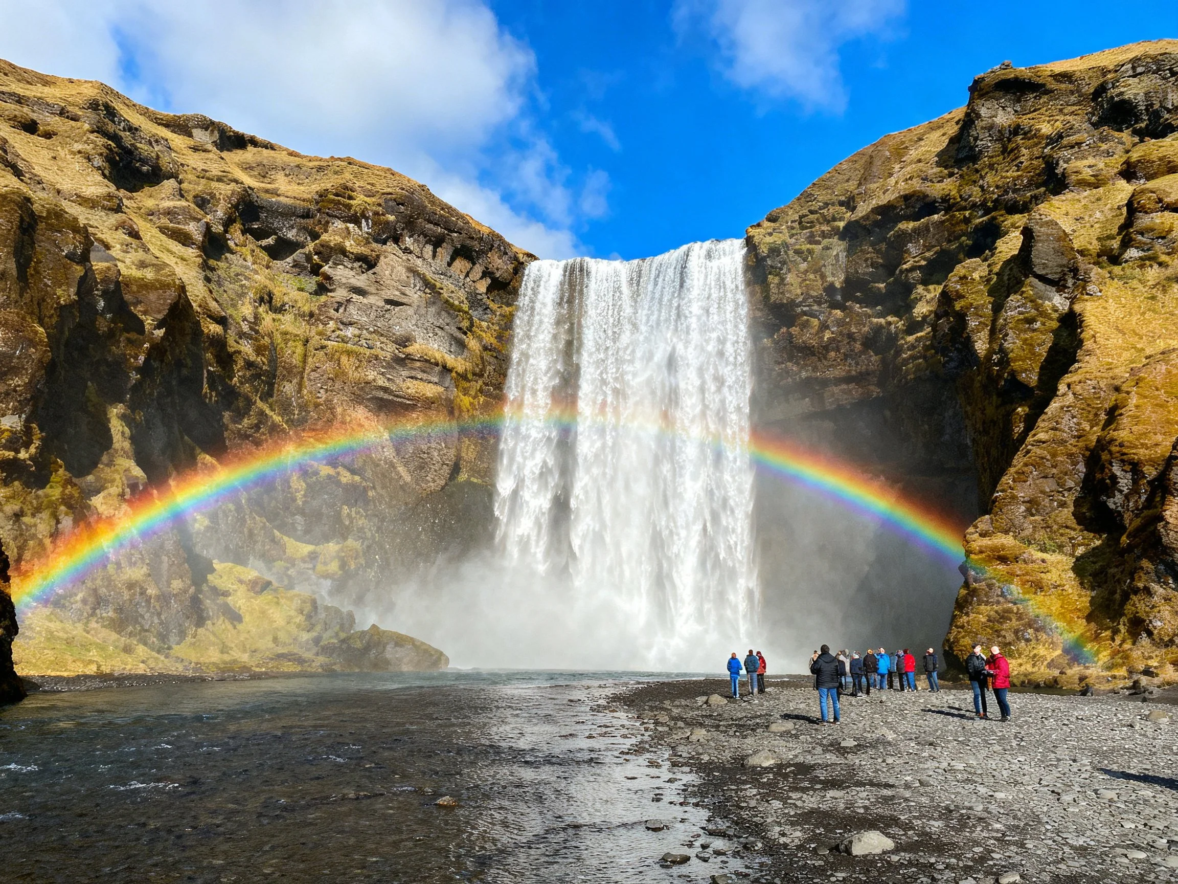A majestic waterfall with vibrant rainbow and rugged cliffs