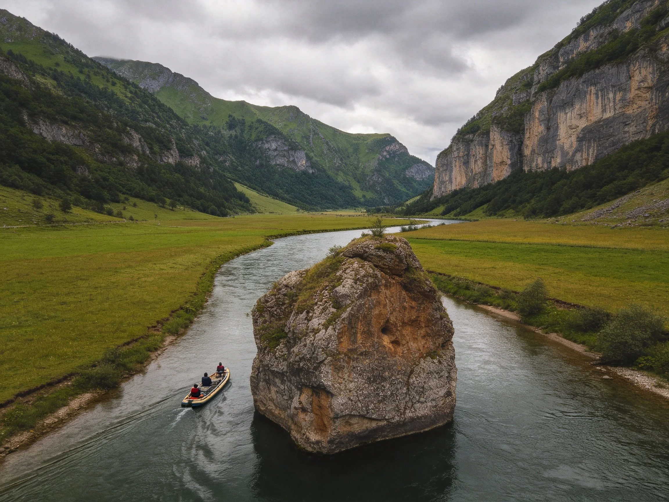A massive rock in a winding river near towering green mountains