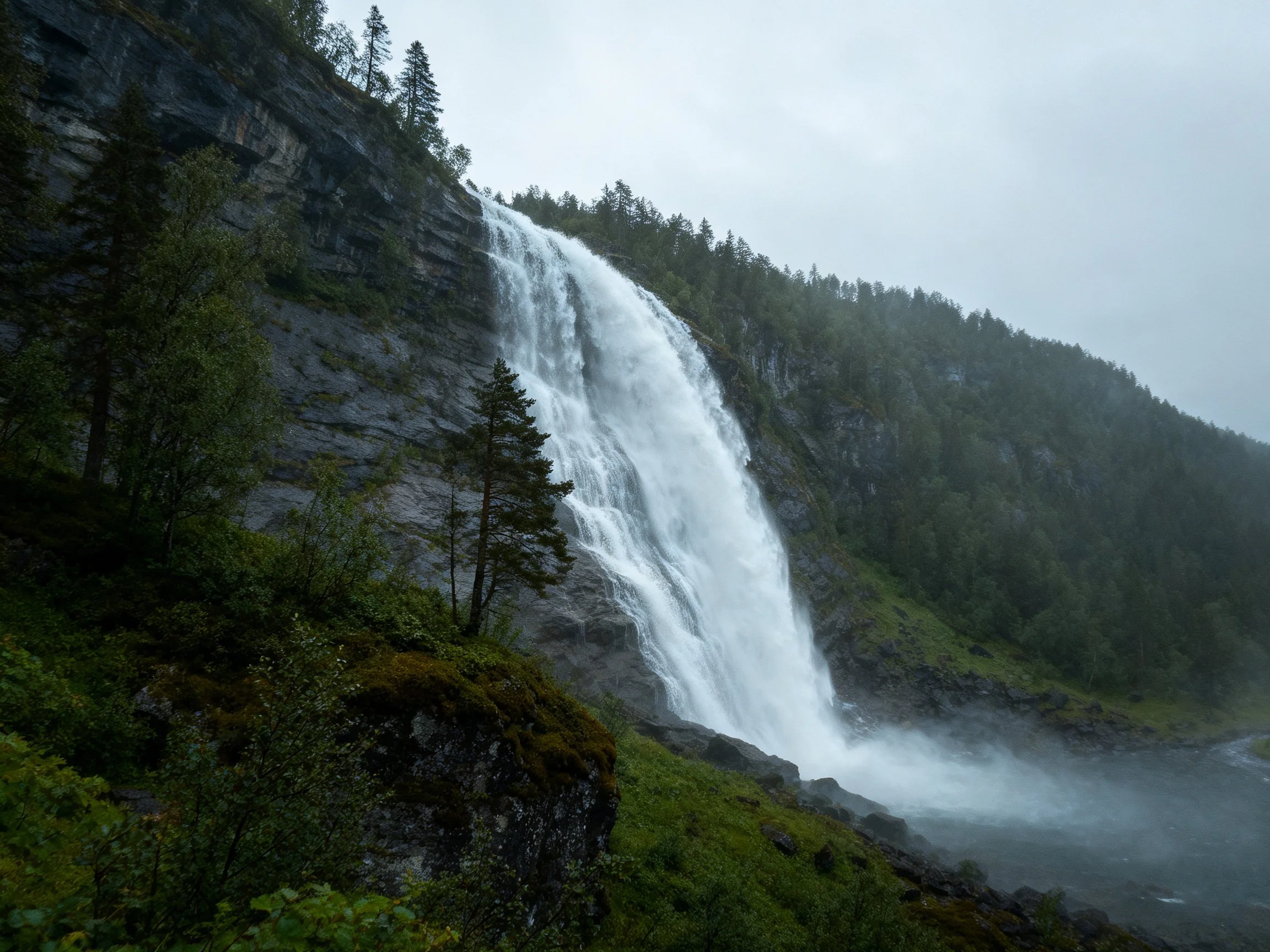 A powerful waterfall cascades down rocky cliffs amid lush greenery