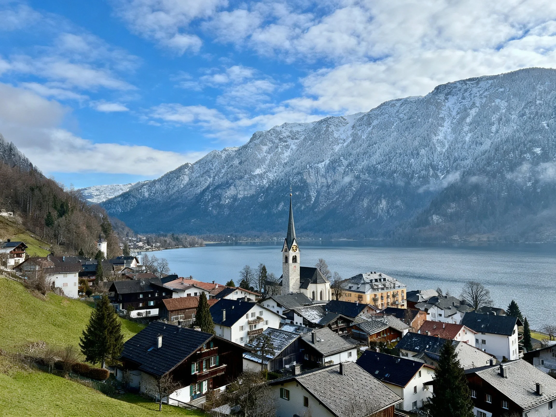 A quaint village with a church, lake, and snow-covered mountains