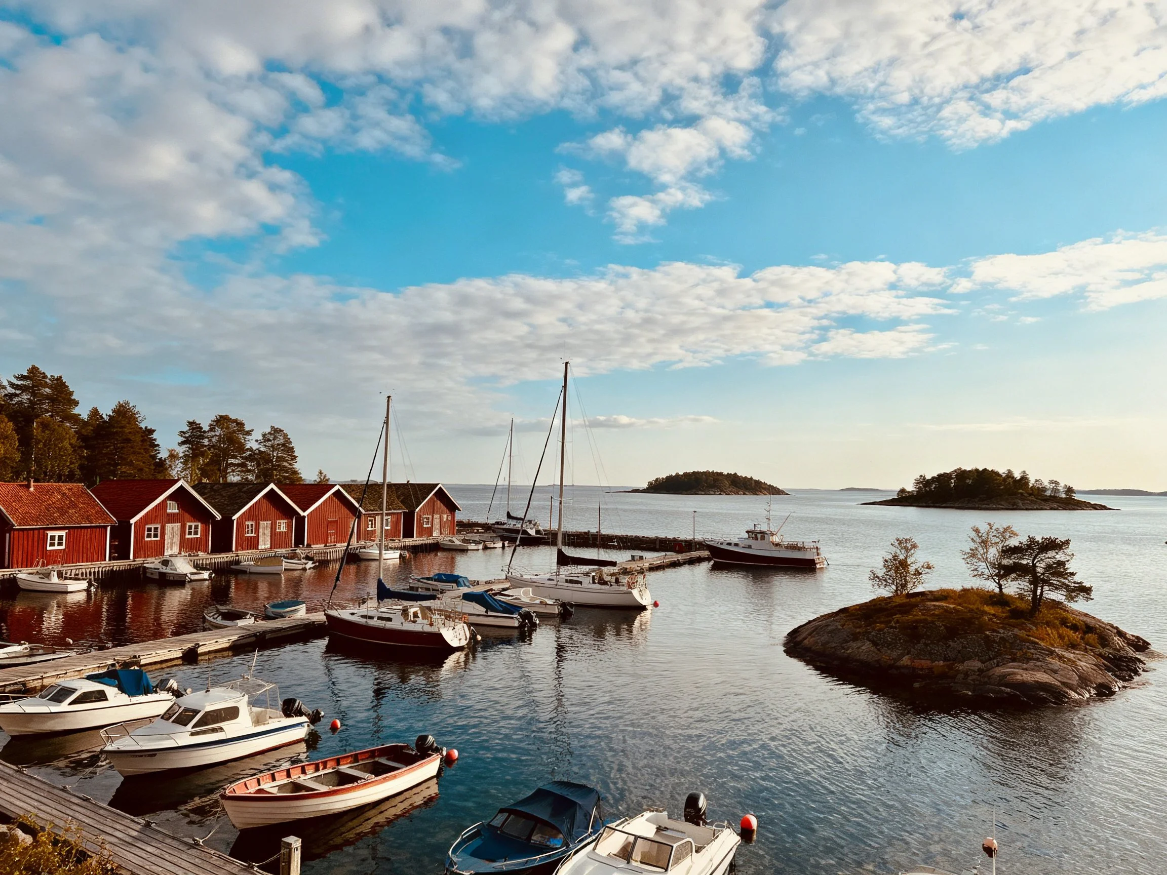 A serene marina with red cabins, docked boats, and small islands