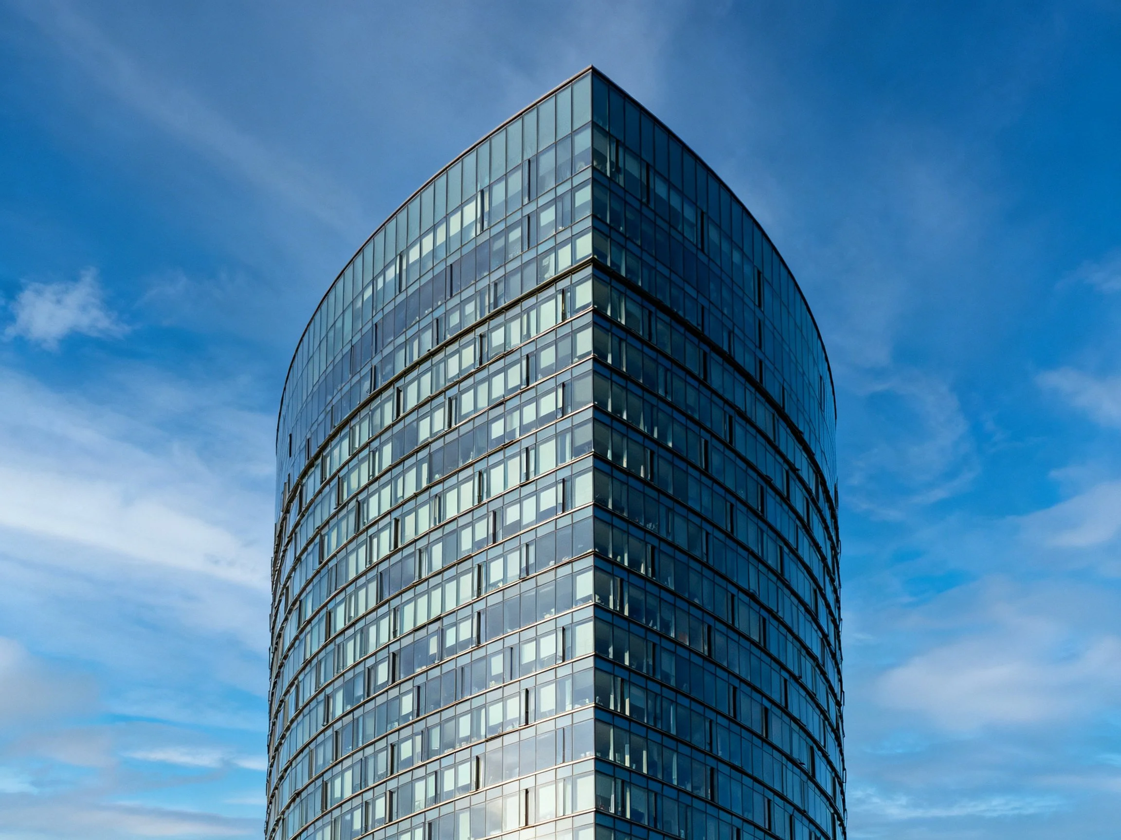 A sleek modern skyscraper with curved glass facade under clear blue sky