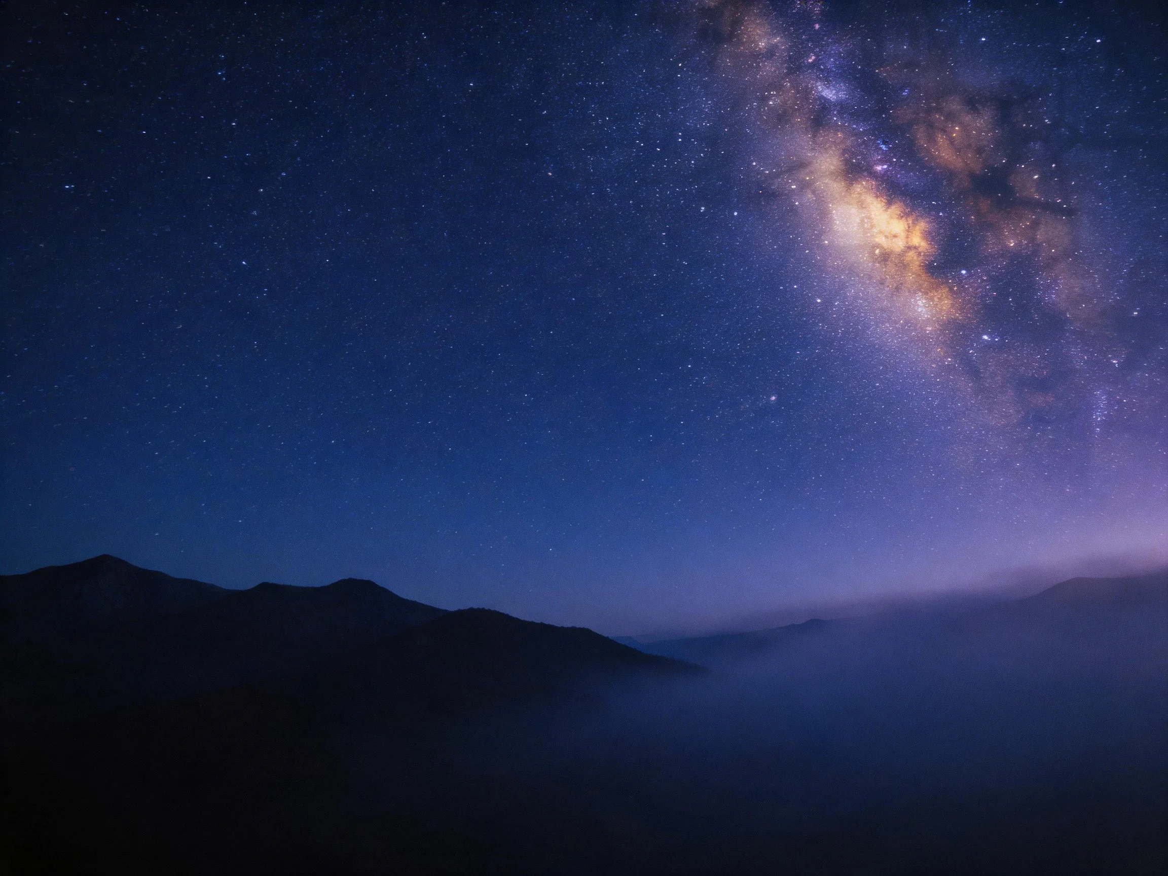 A starry night sky with the Milky Way over mountain silhouettes