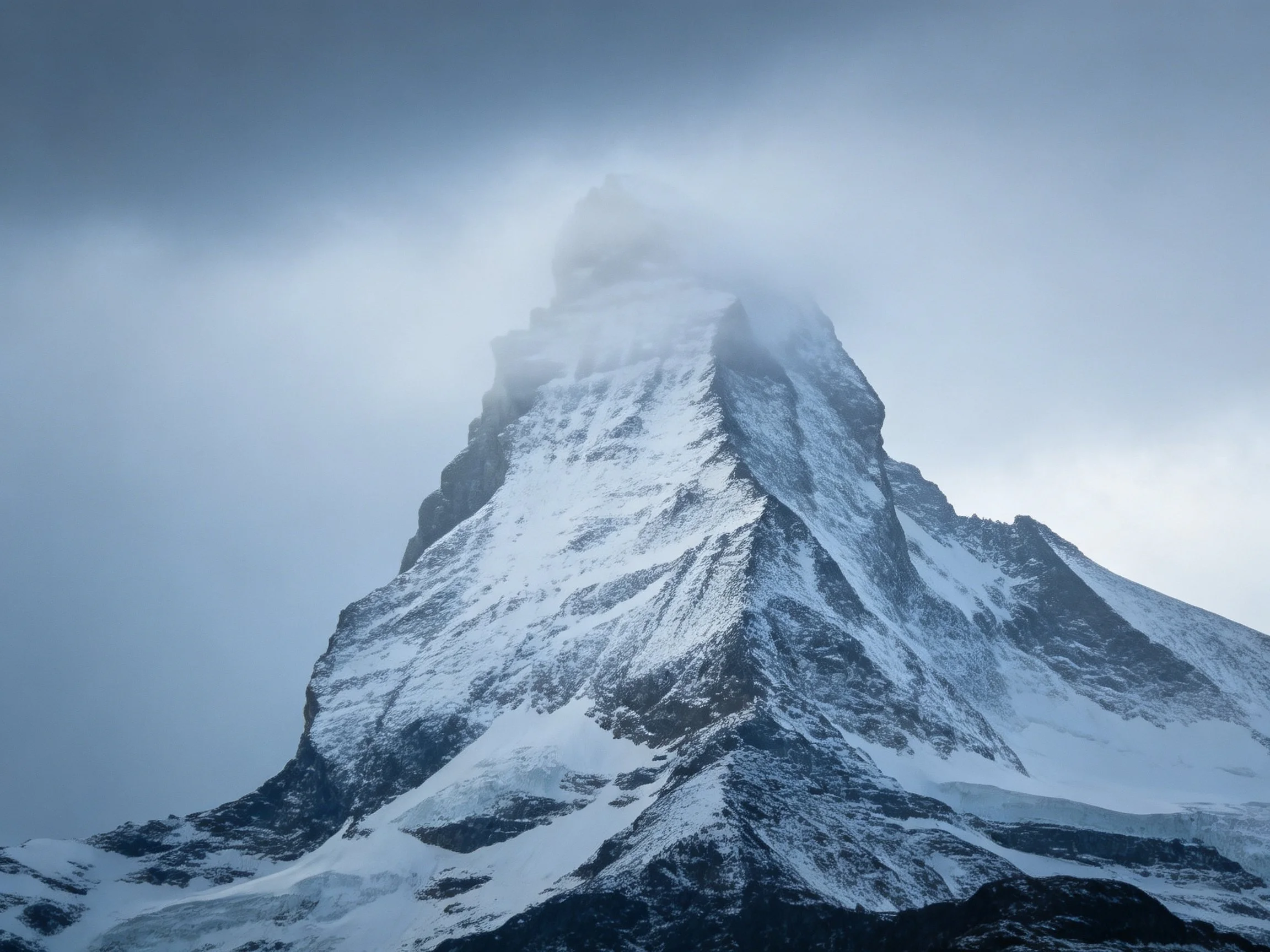 A towering snow-capped mountain peak shrouded in misty clouds
