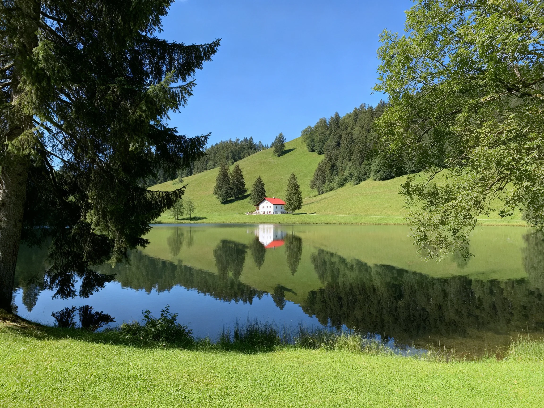 A tranquil lake reflects a white house with red roof amid green hills