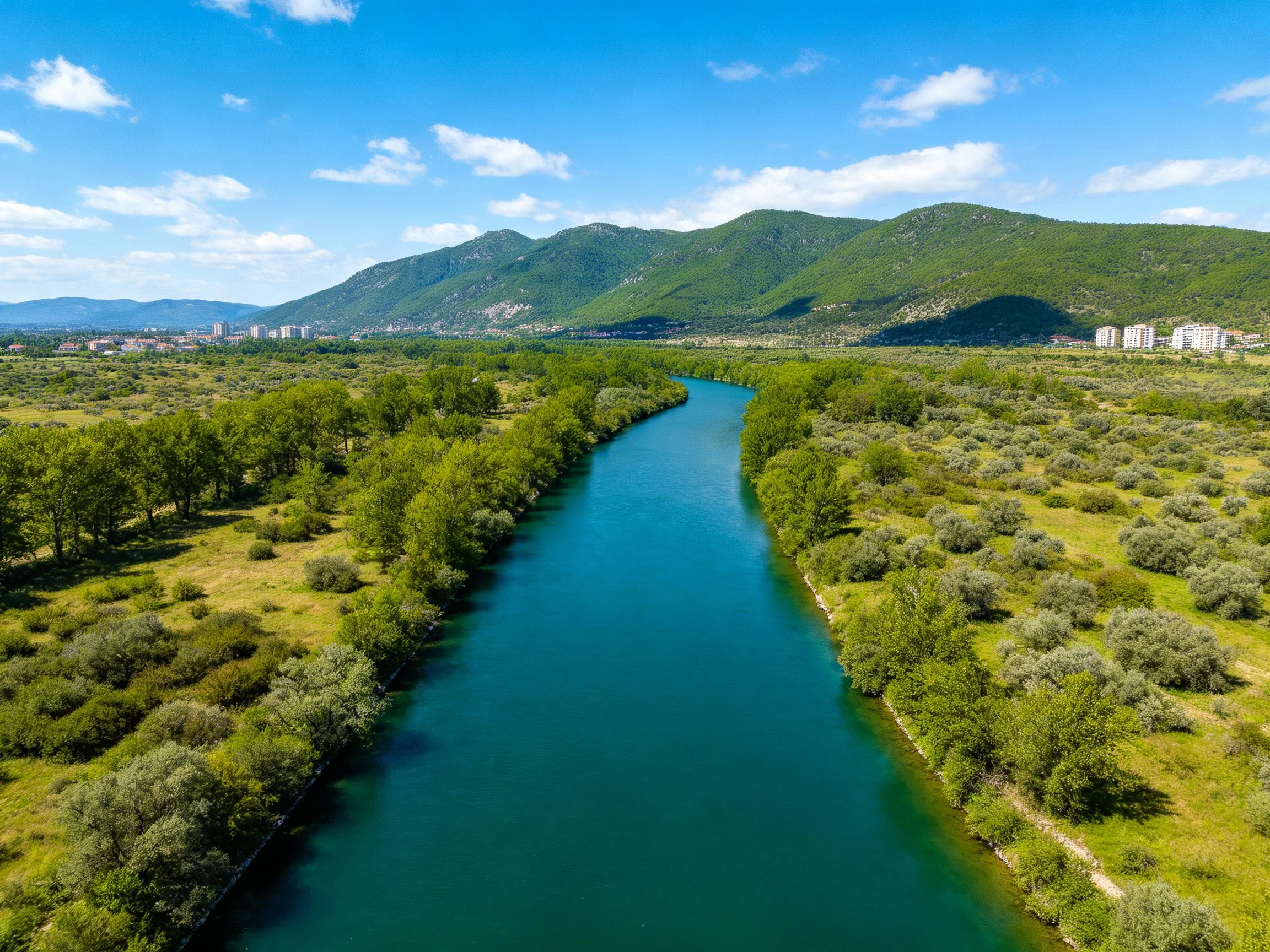 A turquoise river winds through lush green landscapes with distant mountains