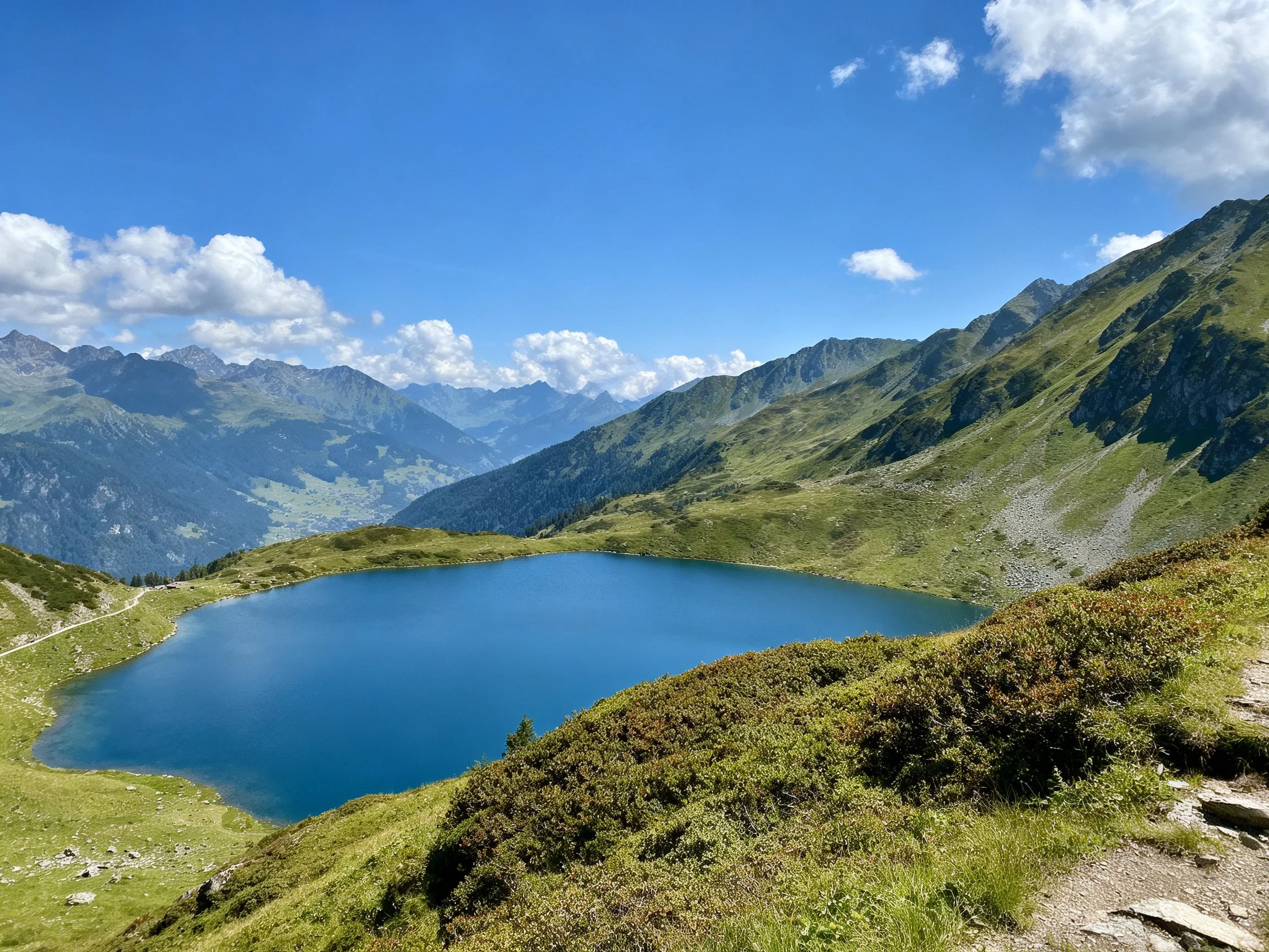 A vibrant blue alpine lake surrounded by lush green mountains