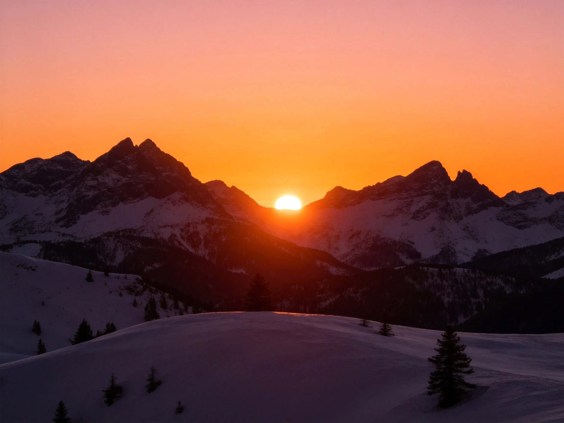 A vibrant sunset illuminates snow-capped mountain peaks