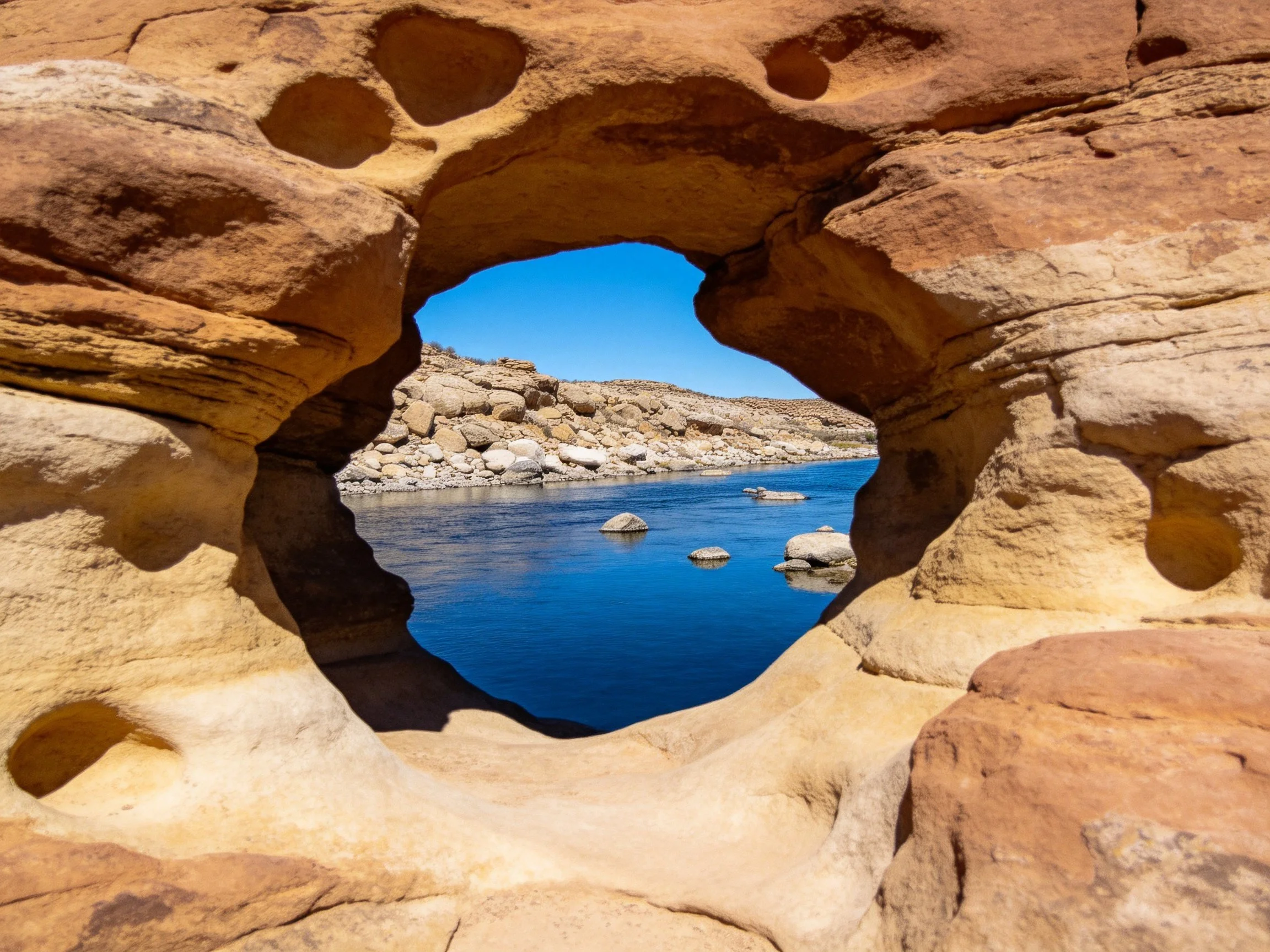 A weathered sandstone arch frames a serene river scene
