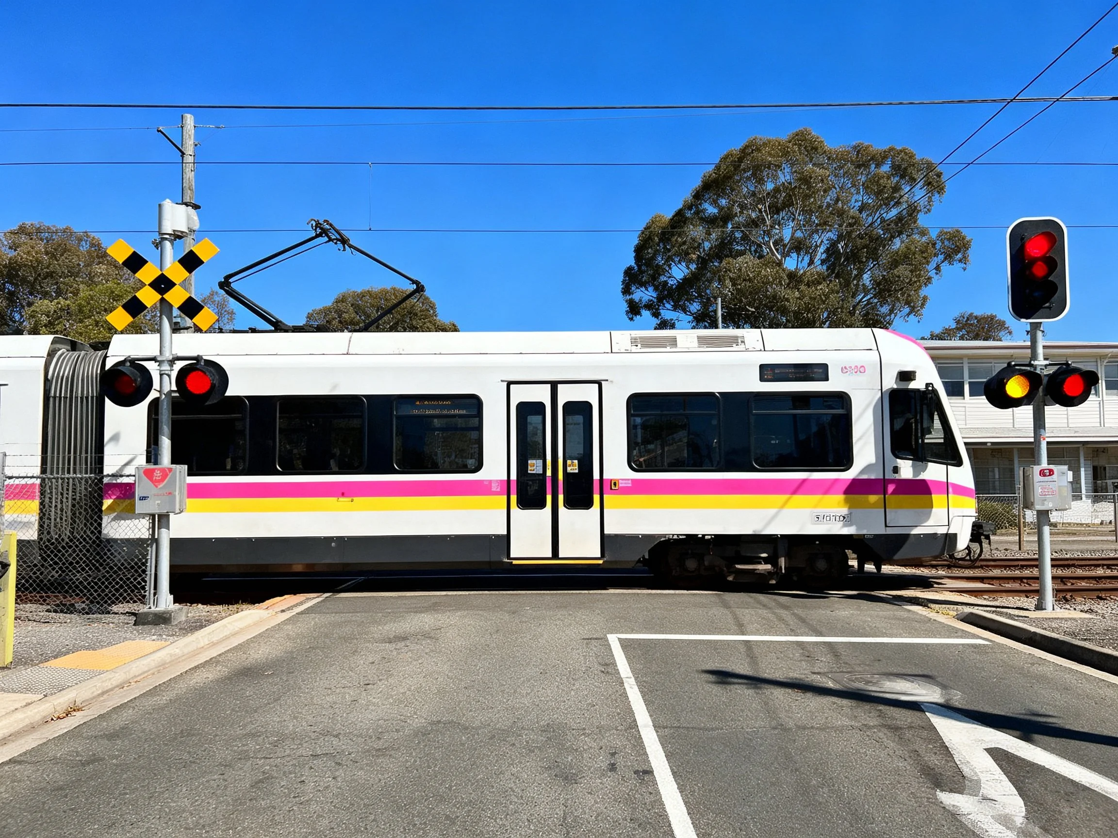 A white and pink striped train crosses a railroad intersection