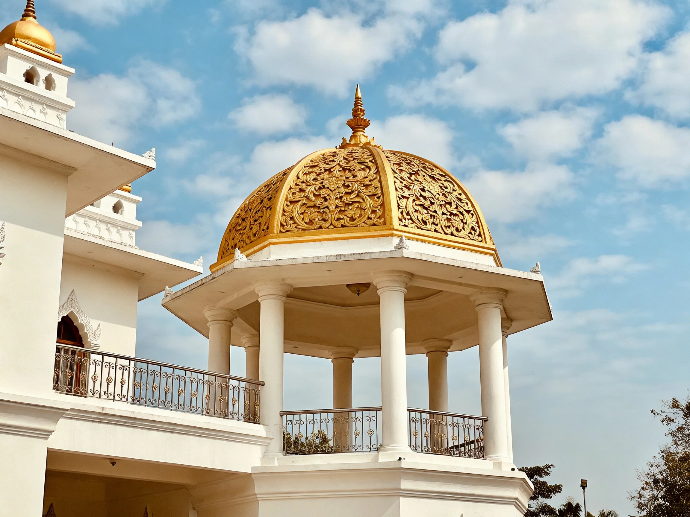 A white architectural structure with ornate golden domes and columns
