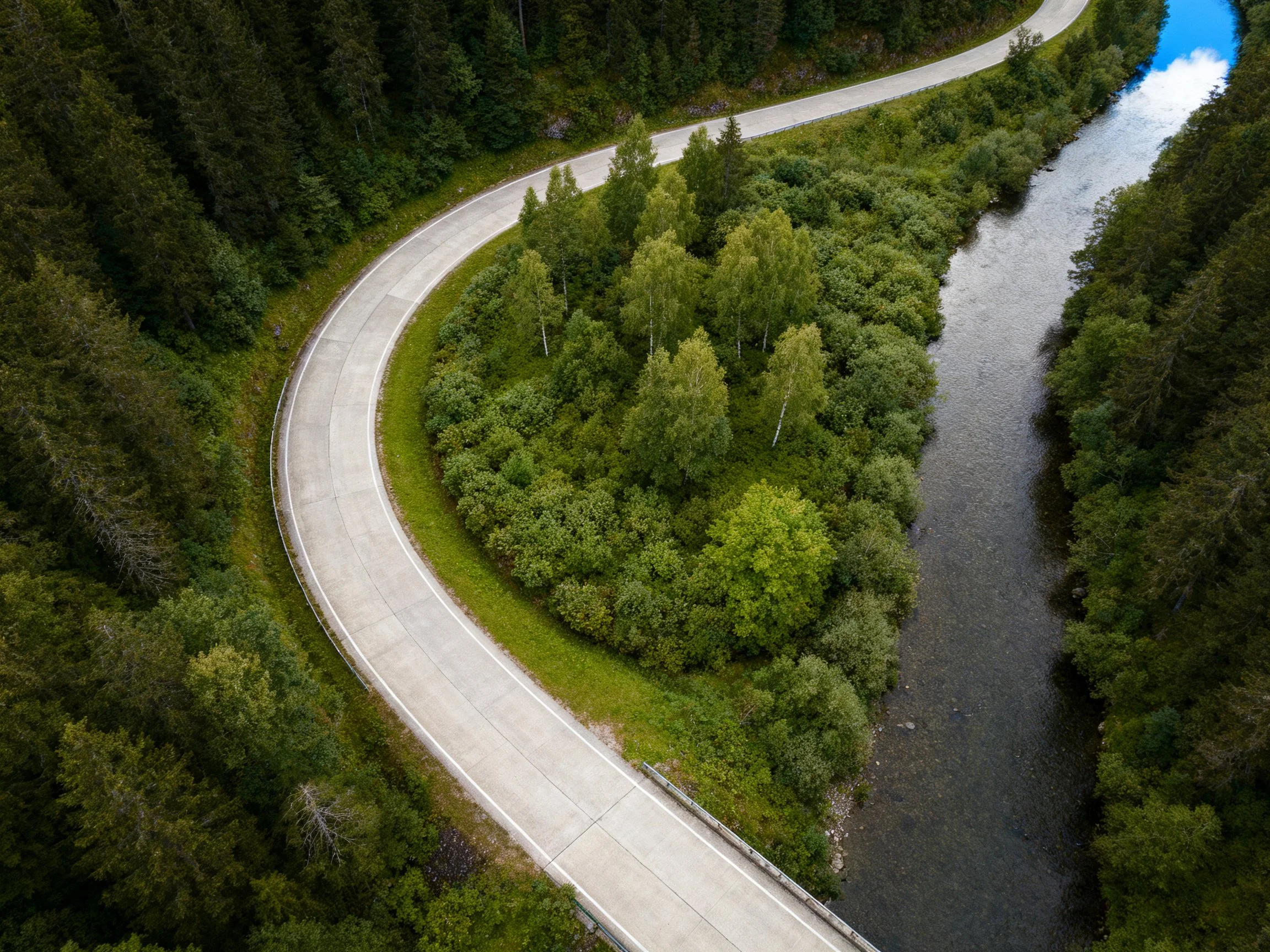 A winding road curves beside a forested river