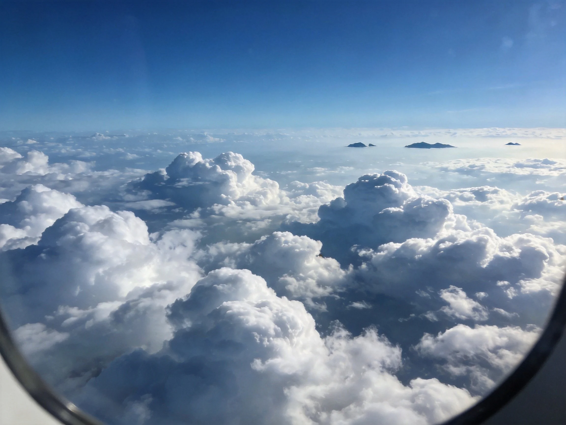 Aerial View Through Airplane Window: Blue Sky and Cumulus Clouds