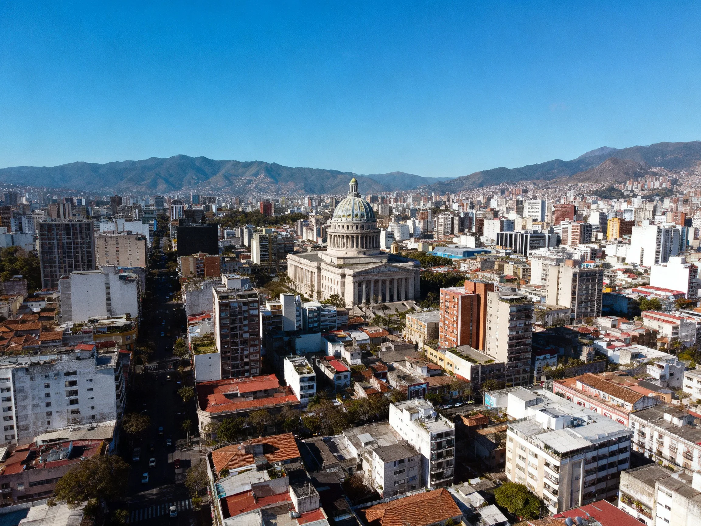 Aerial view of a city with a grand domed central building and mountainous backdrop
