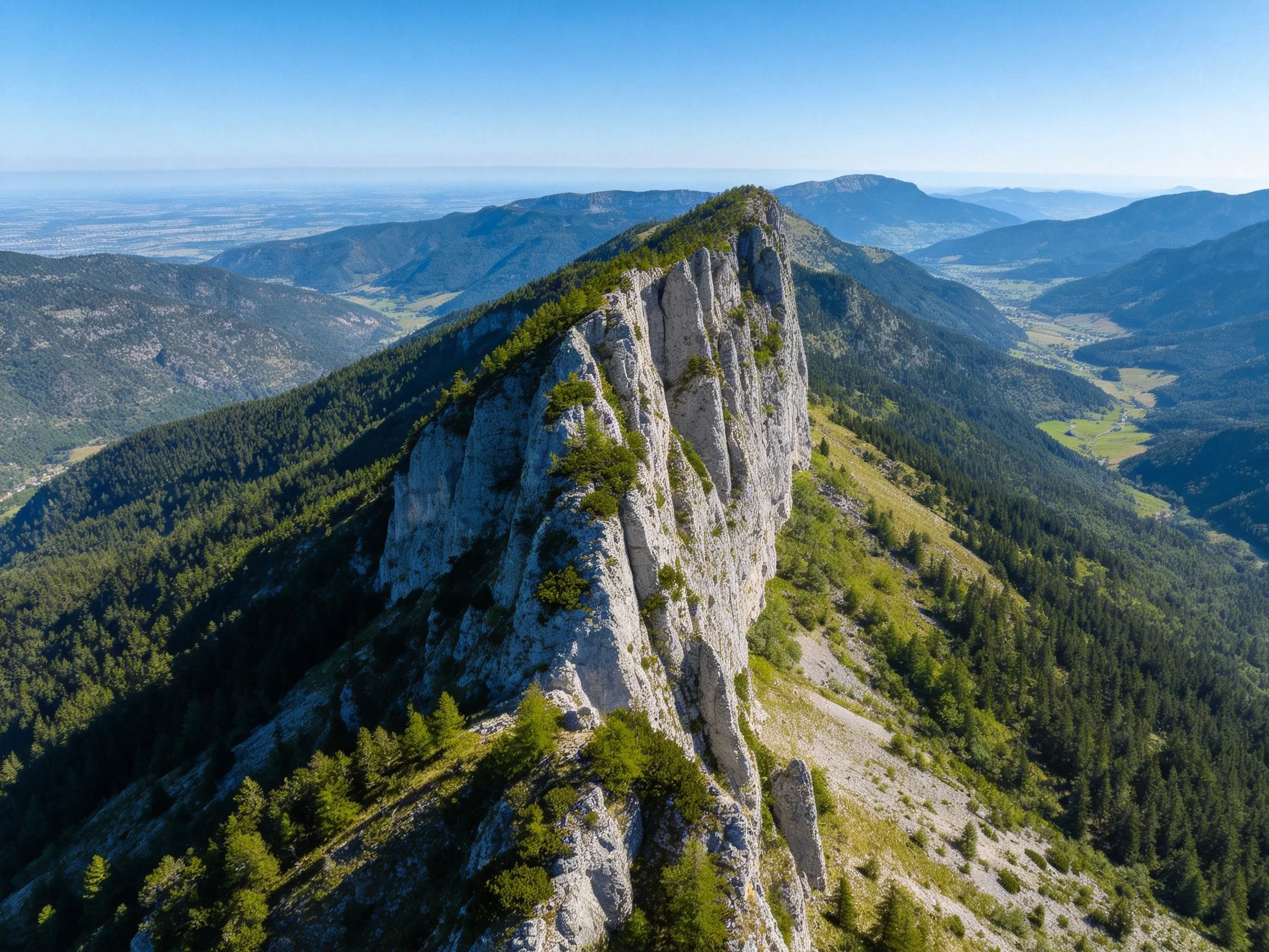 Aerial view of dramatic limestone cliff with forested mountain slopes