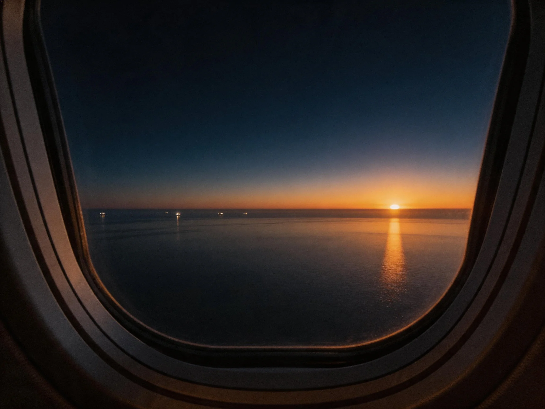 Airplane Window View of Sunset Over Calm Waters