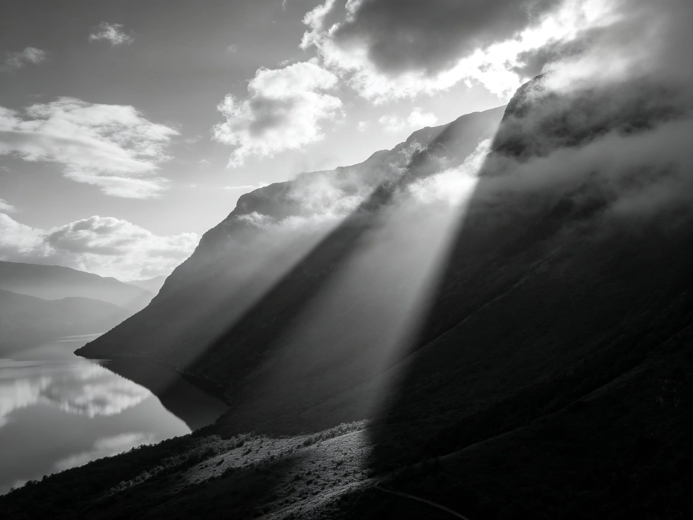 Black-and-white mountain landscape with sunbeams and misty peaks