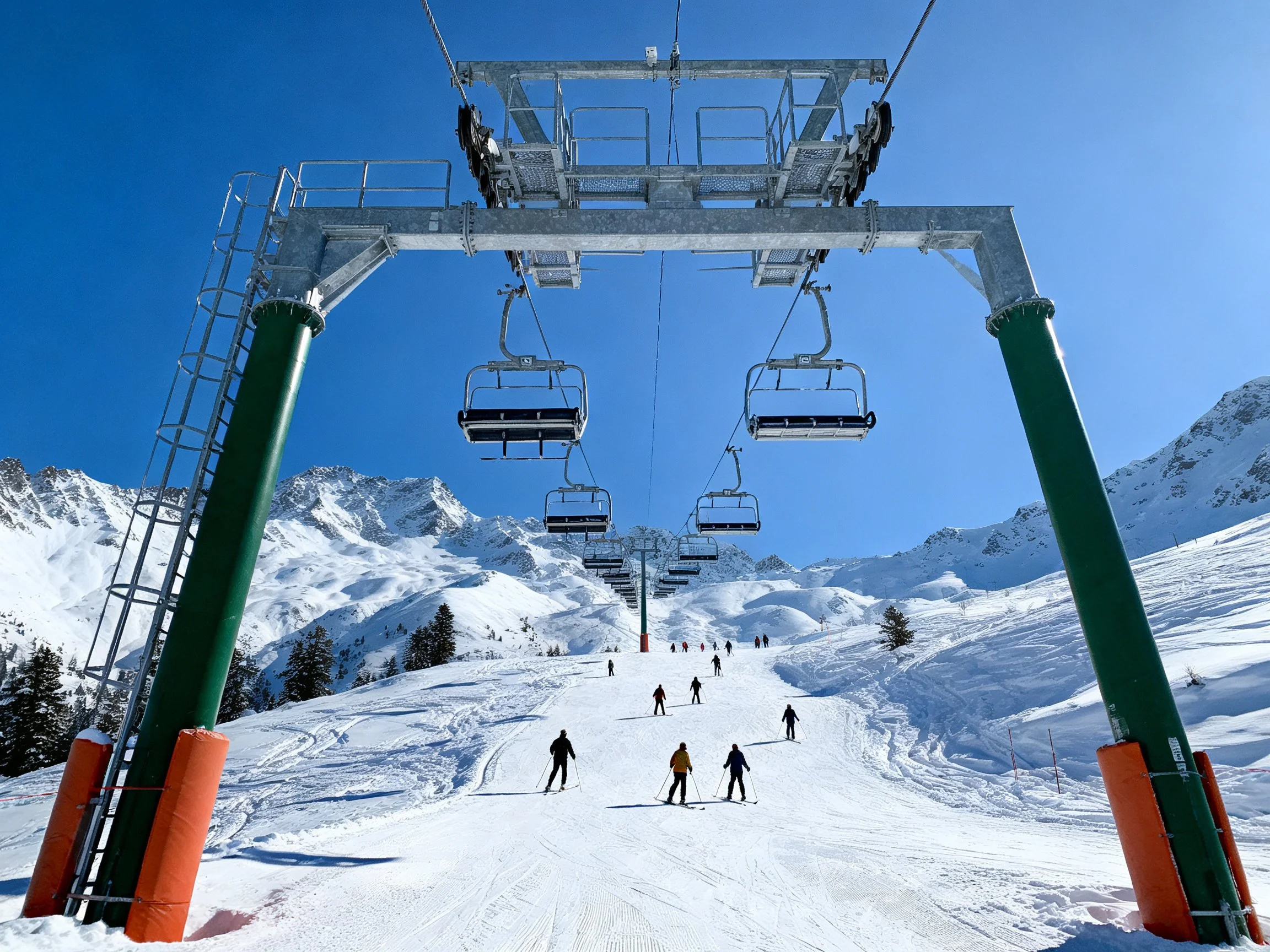 Chairlift Over Snow-Covered Slope With Skiers and Mountain Peaks