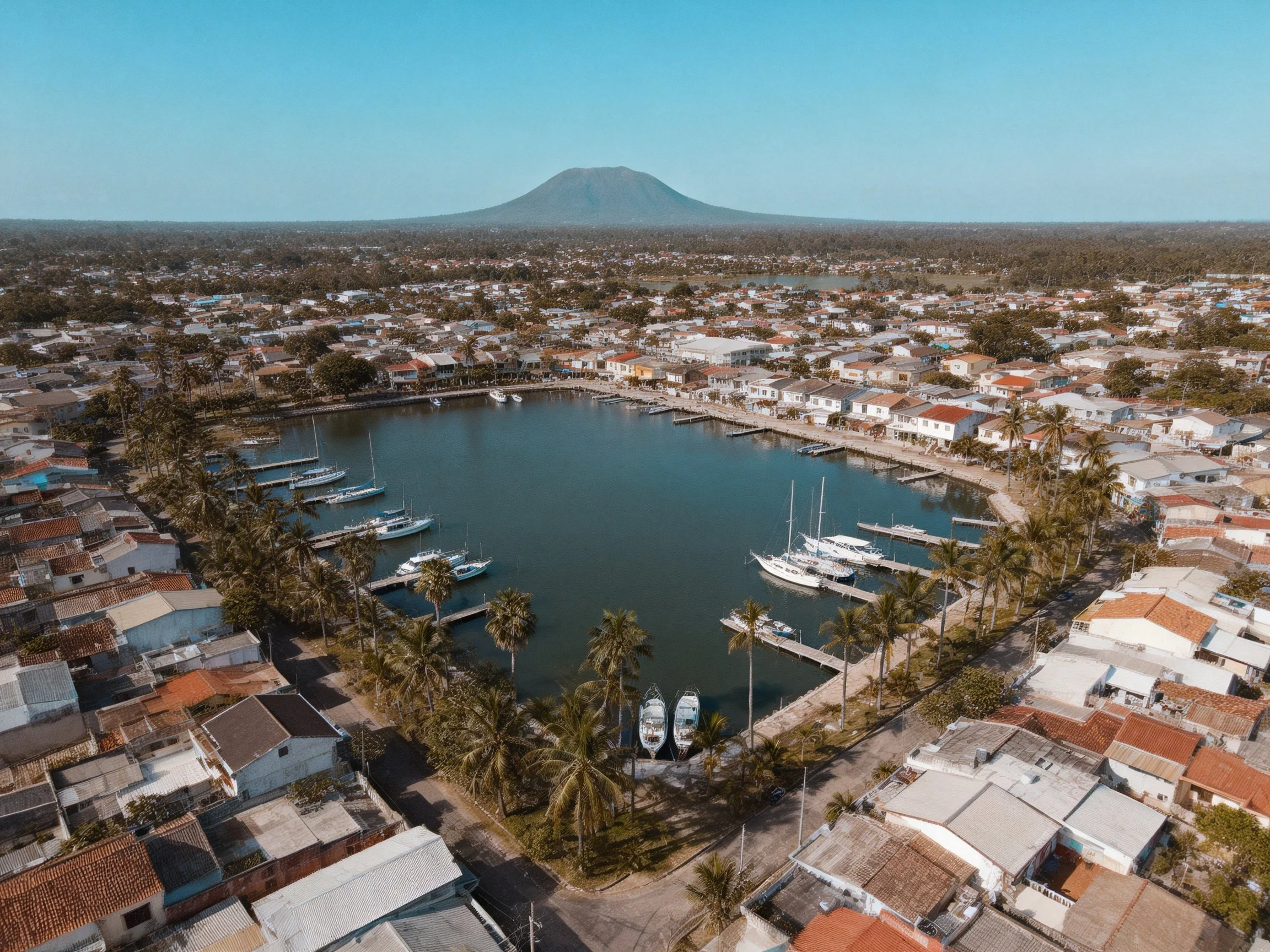 Coastal Town Marina with Docked Boats, Homes, and Distant Volcano