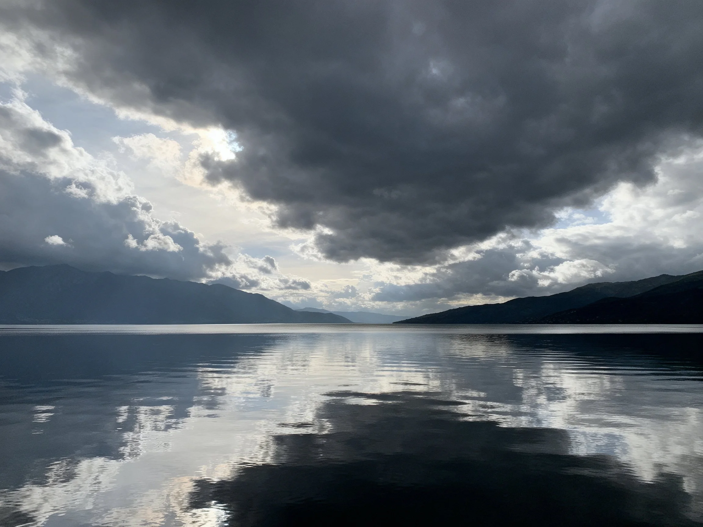 Dark storm clouds over calm reflective lake waters