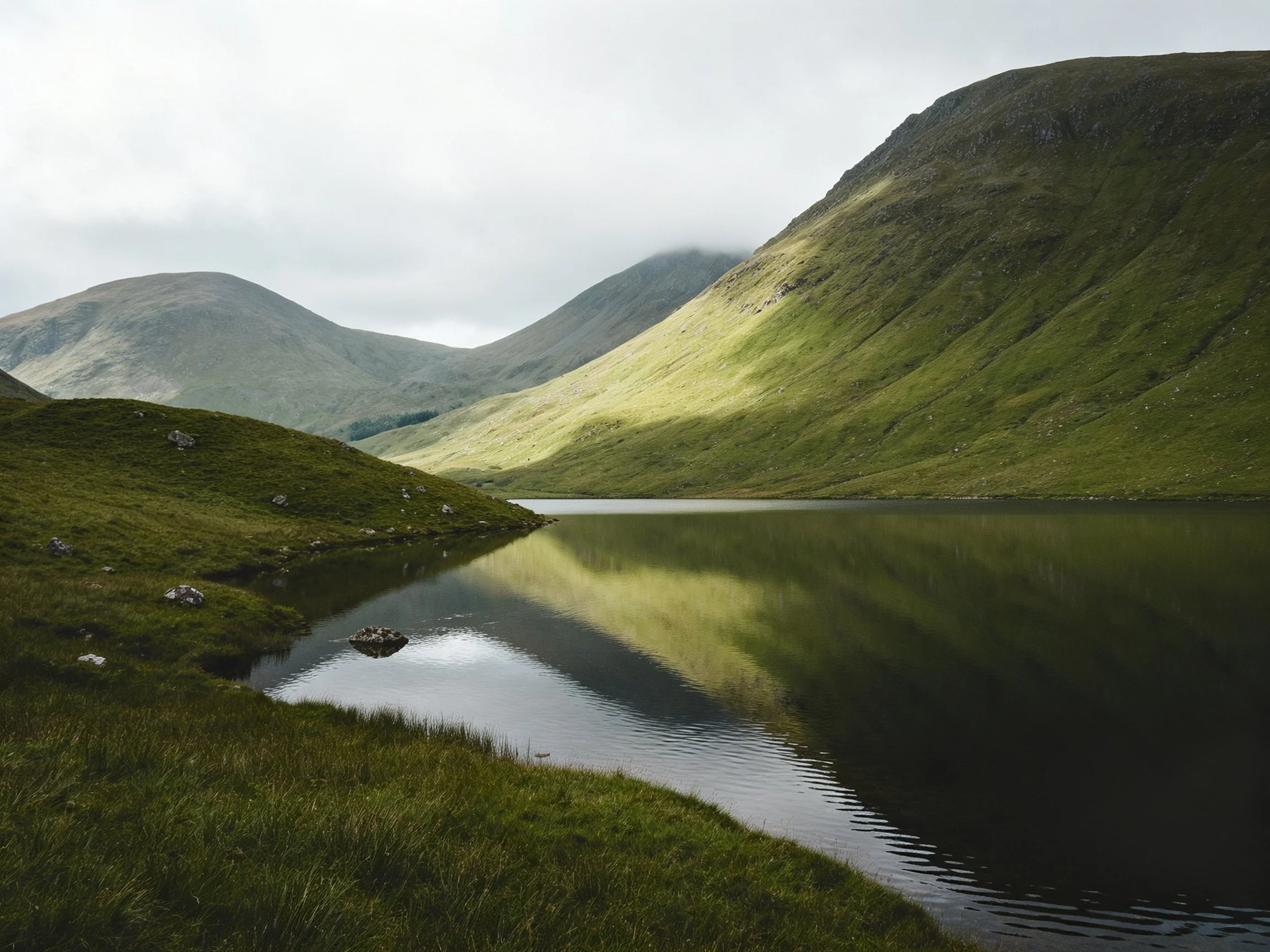 Dense Green Hills Reflecting in a Calm Mountain Lake