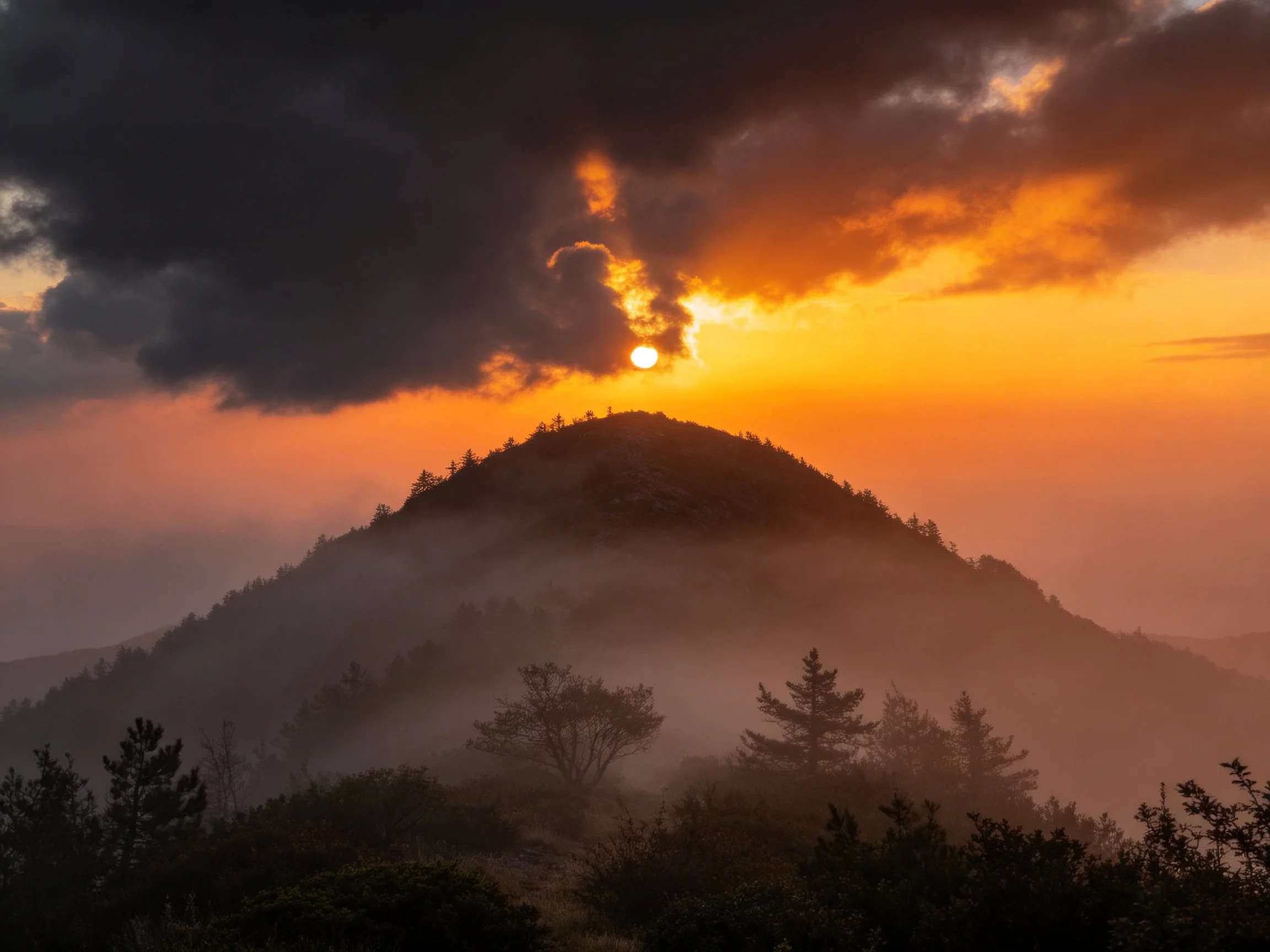 Dramatic mountain sunrise with golden light and dark storm clouds