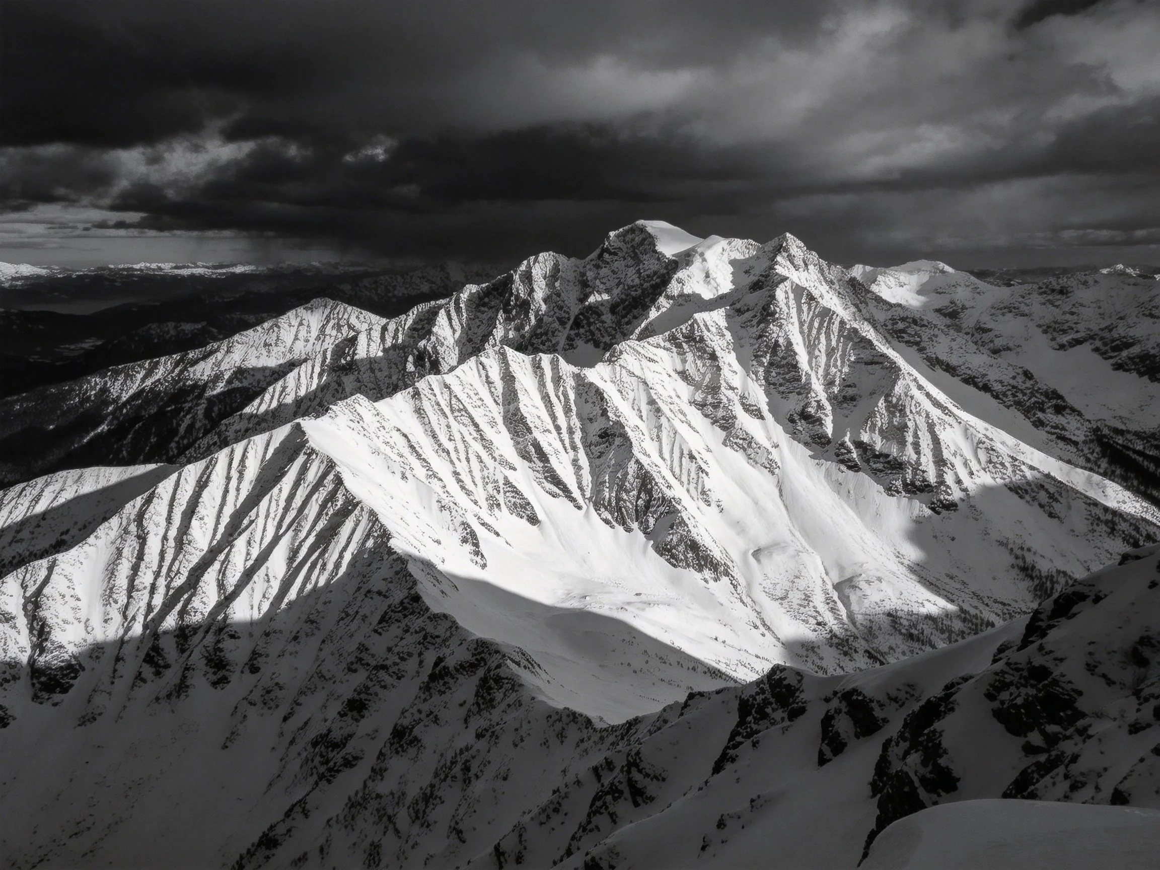 Dramatic snow-capped mountain peaks against dark storm clouds