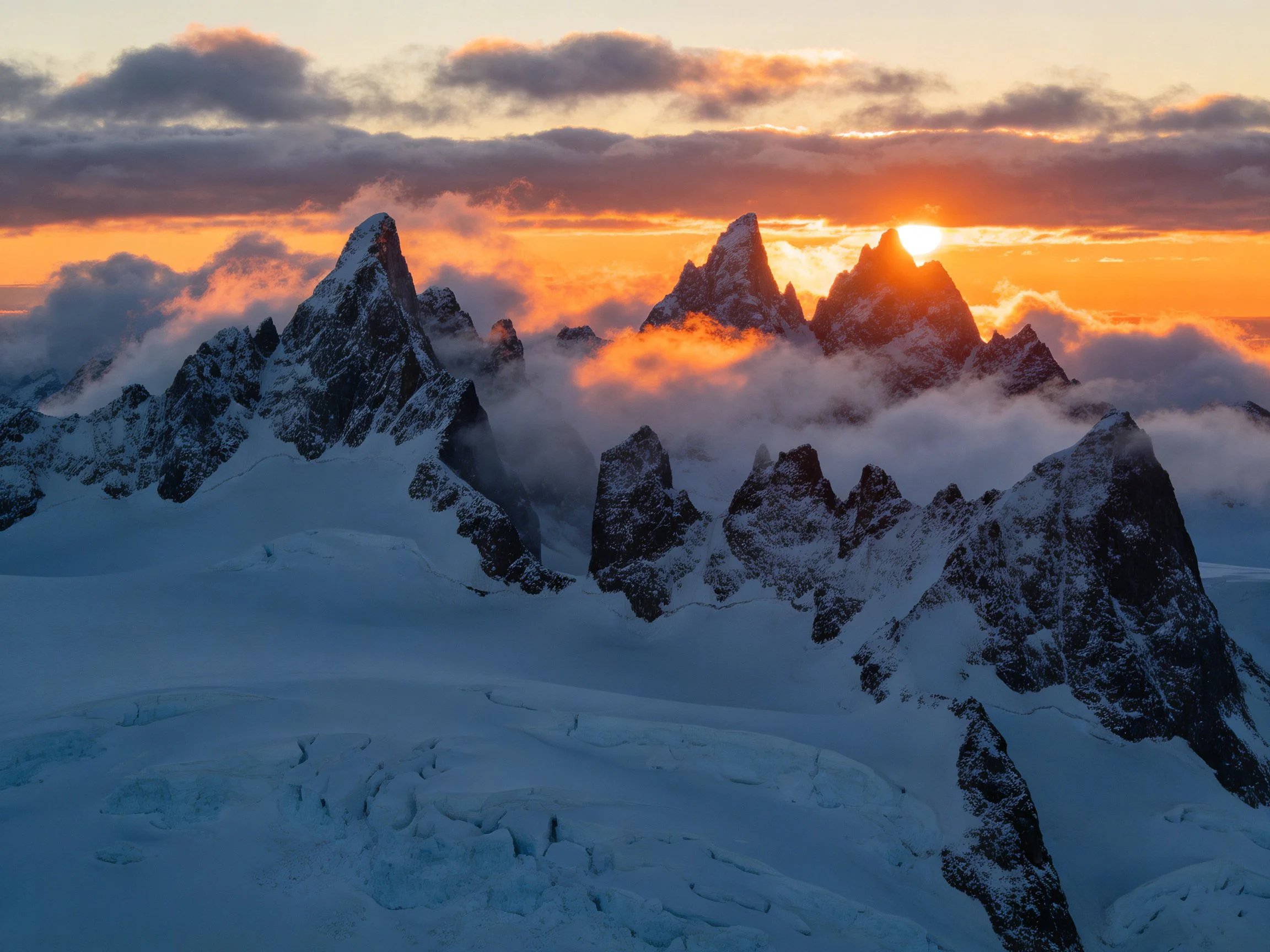 Dramatic snow-capped mountain peaks with fiery sunset glow
