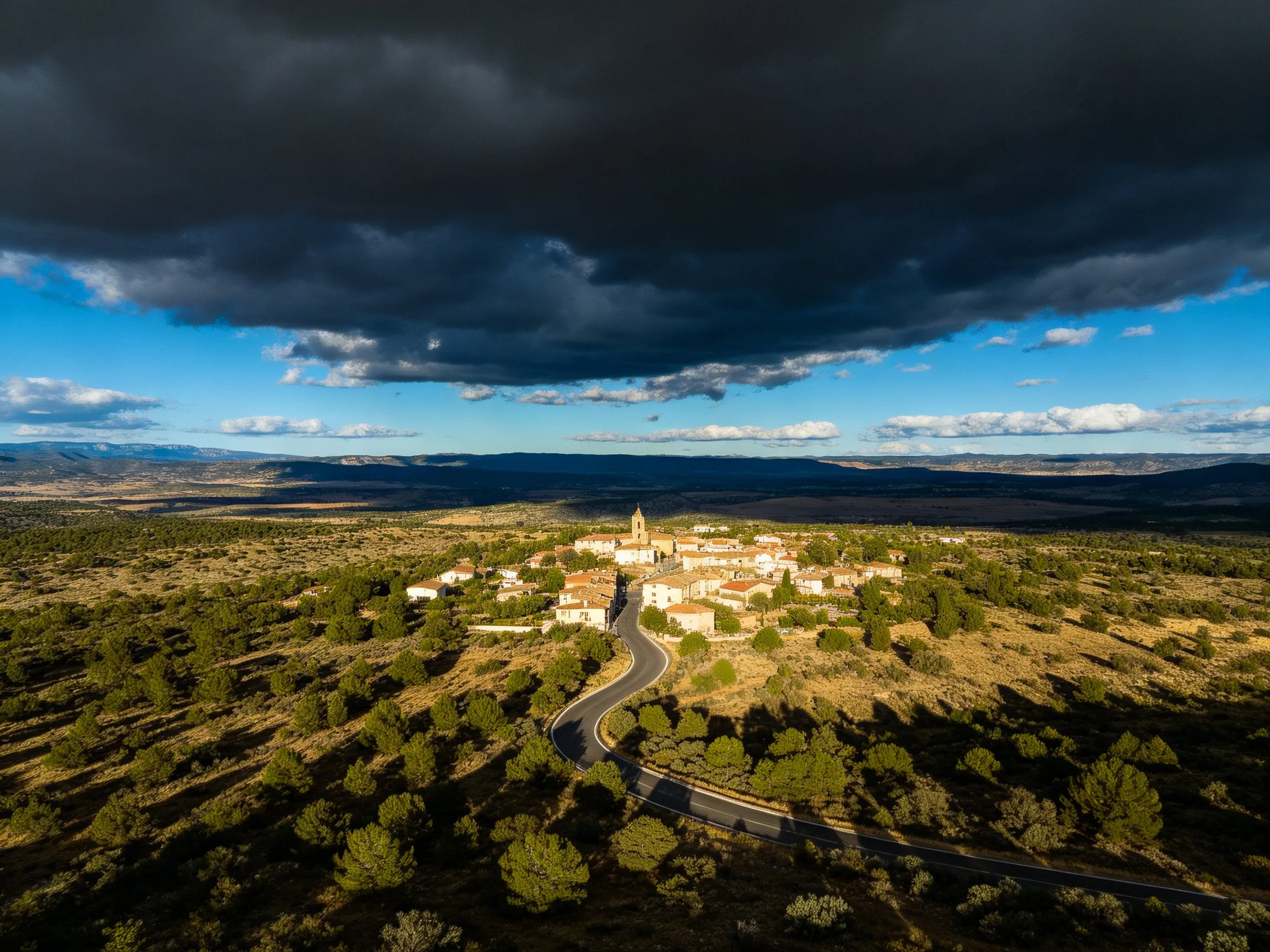 Dramatic storm clouds hover over a secluded village amid varied terrain