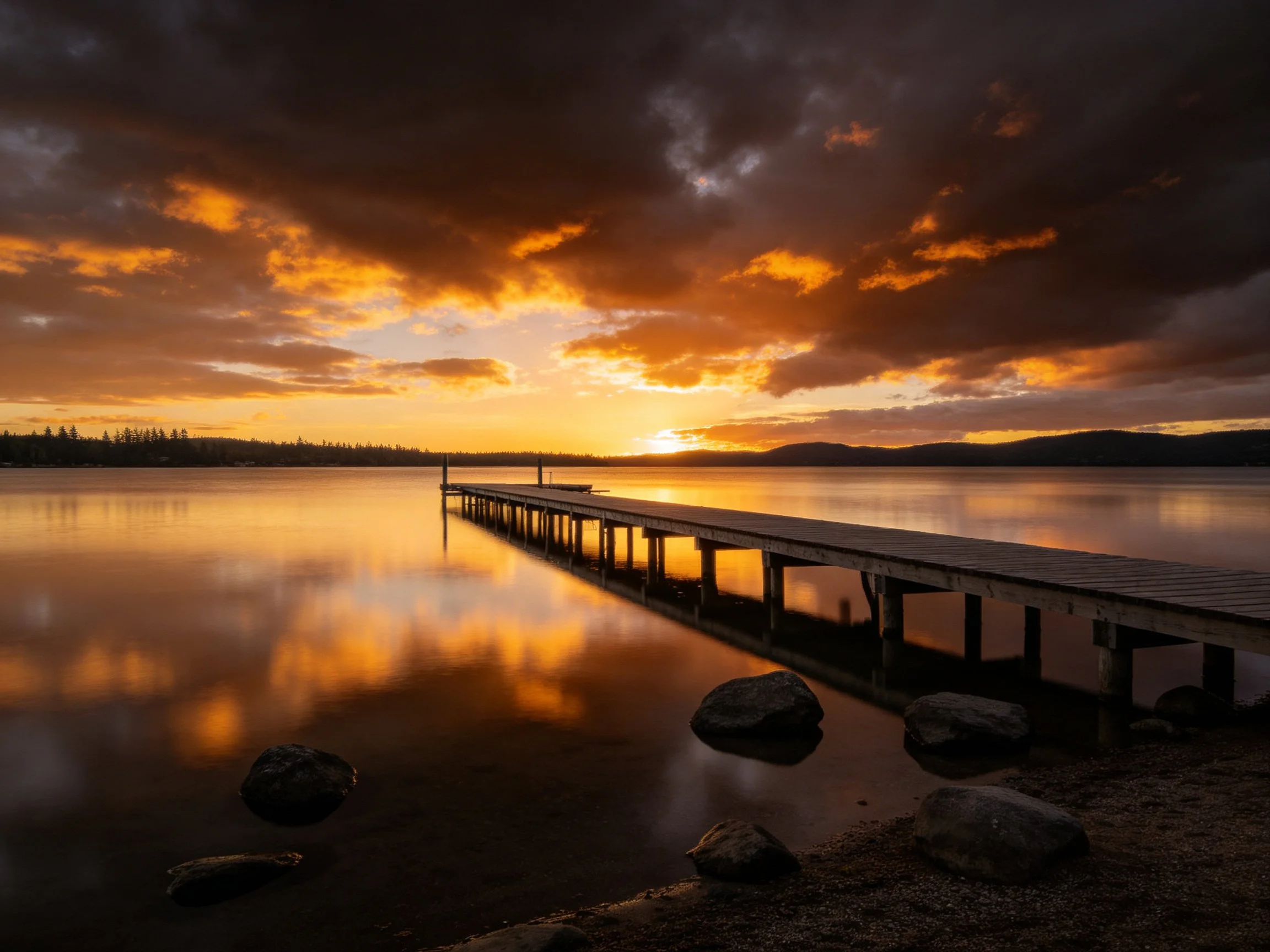 Dramatic sunset over calm lake with wooden pier