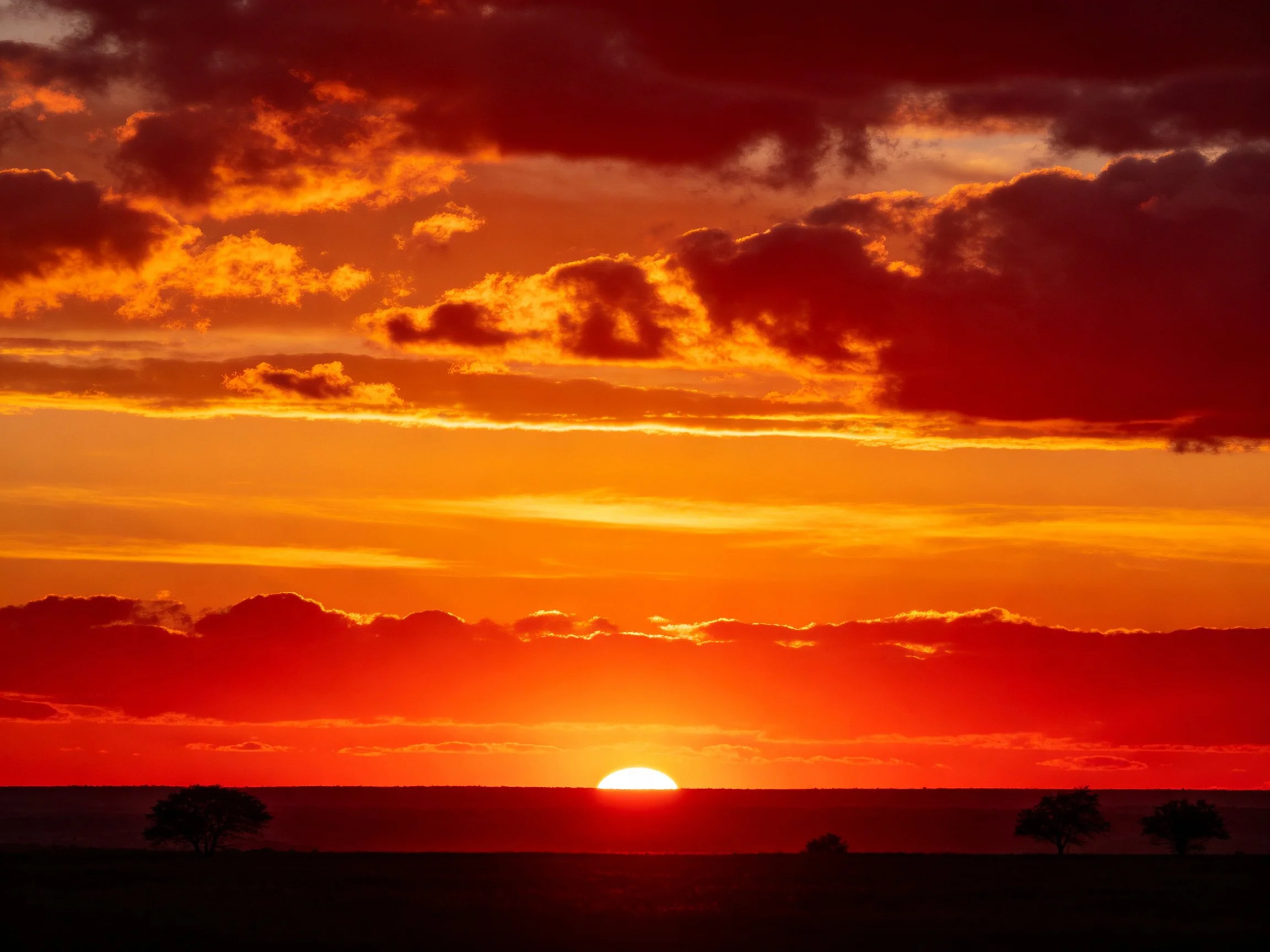 Dramatic sunset with fiery orange clouds over distant horizon